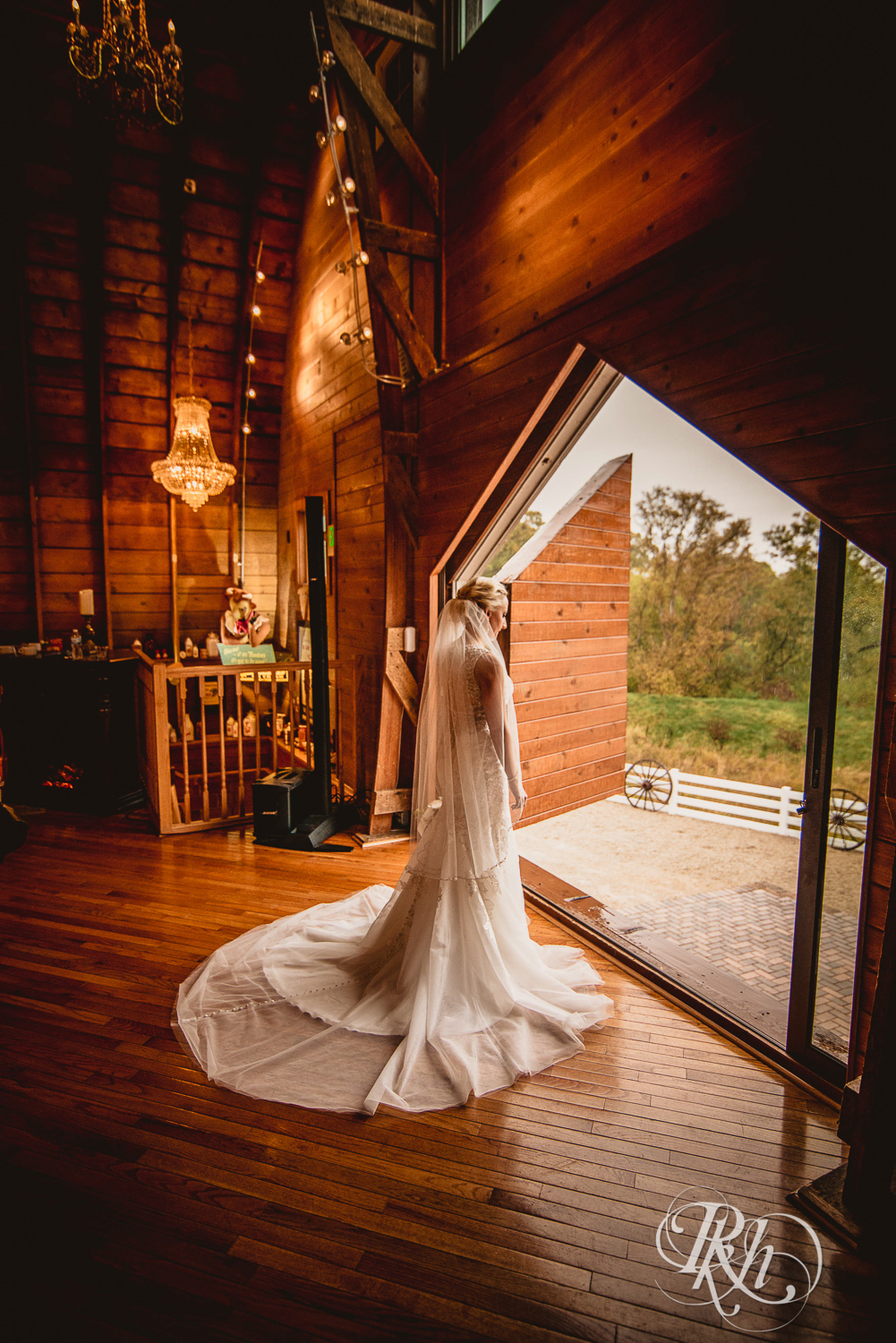 Bride stands in front of large window at Green Acres Event Center barn wedding in Eden Prairie, Minnesota.