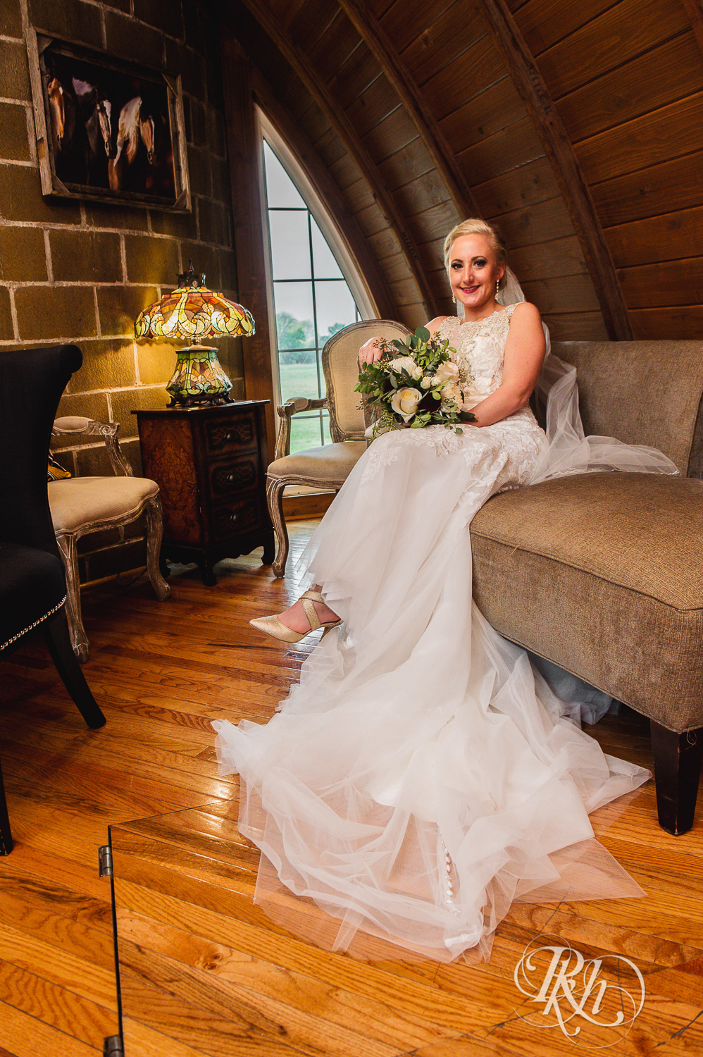 Bride sits on couch at Green Acres Event Center barn wedding in Eden Prairie, Minnesota.