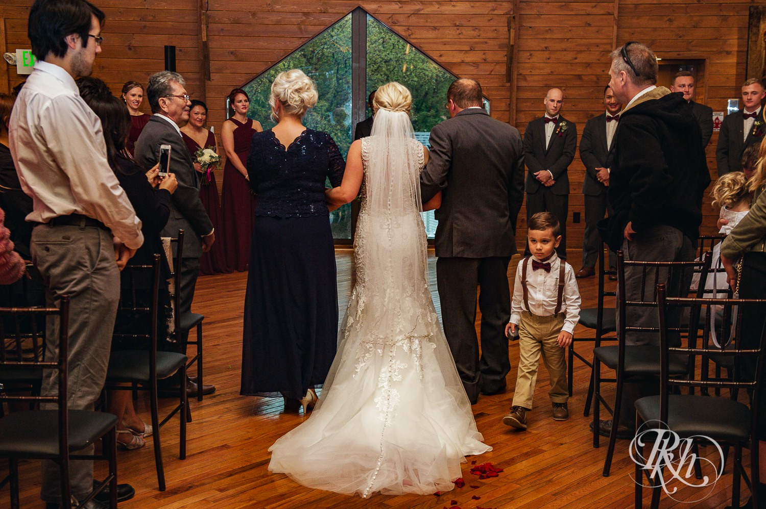 Bride walks down the aisle with parents at Green Acres Event Center barn wedding ceremony in Eden Prairie, Minnesota.