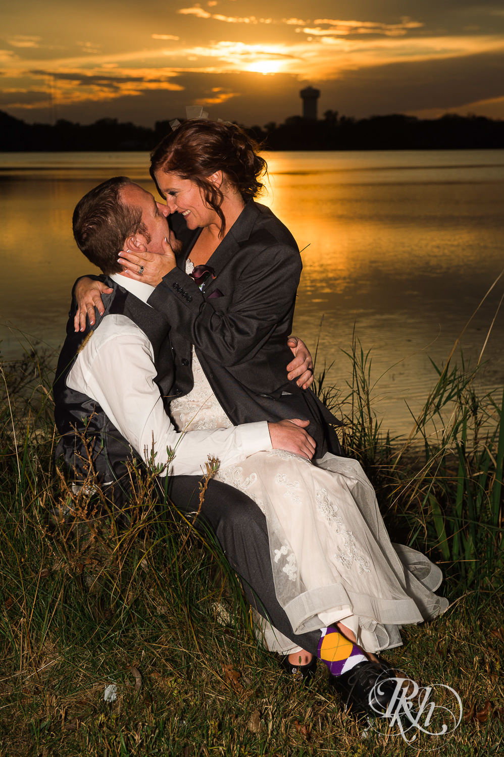Bride and groom smile at sunset in front of the lake in White Bear Lake, Minnesota.