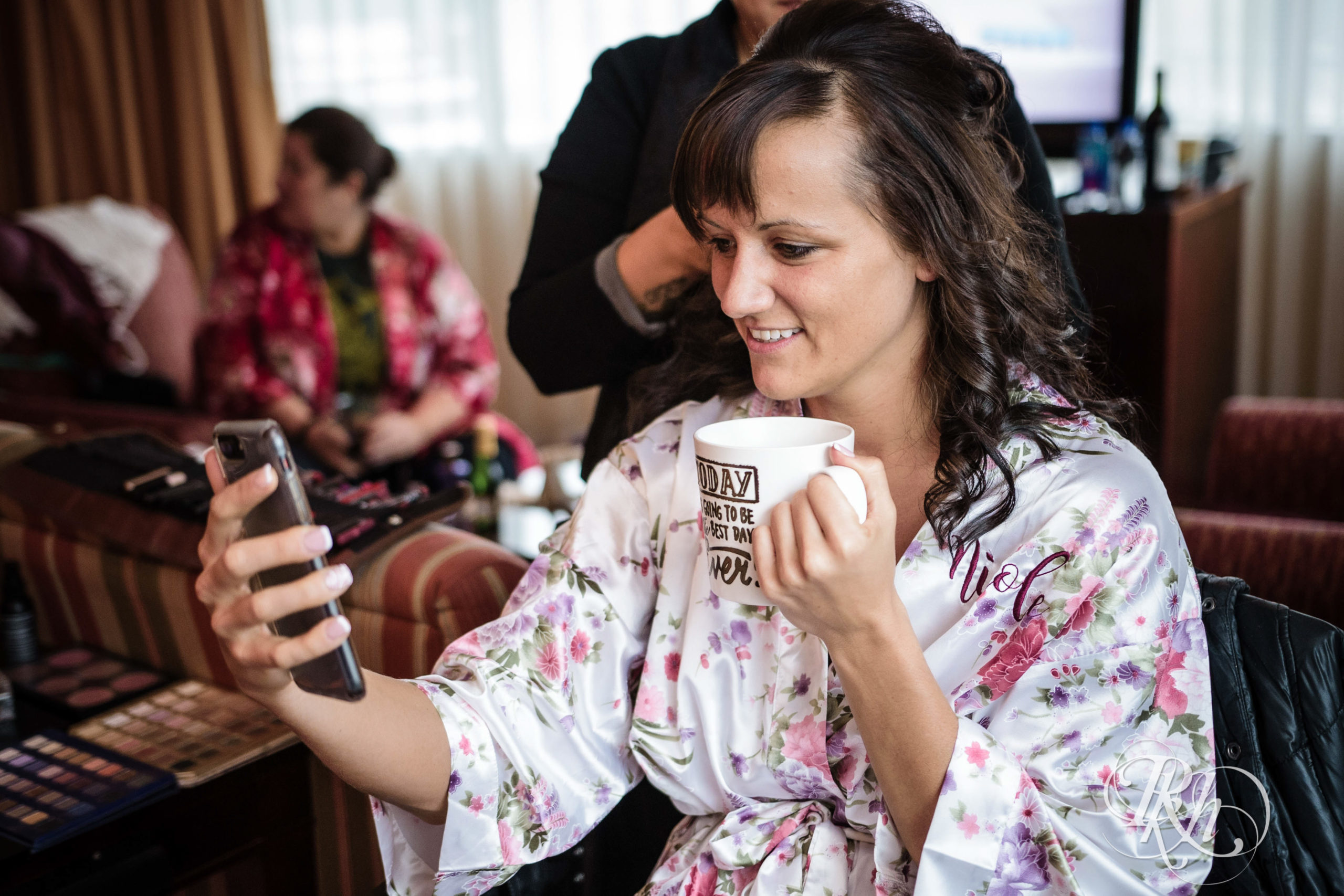 Bride holds coffee cup while talking on phone. 