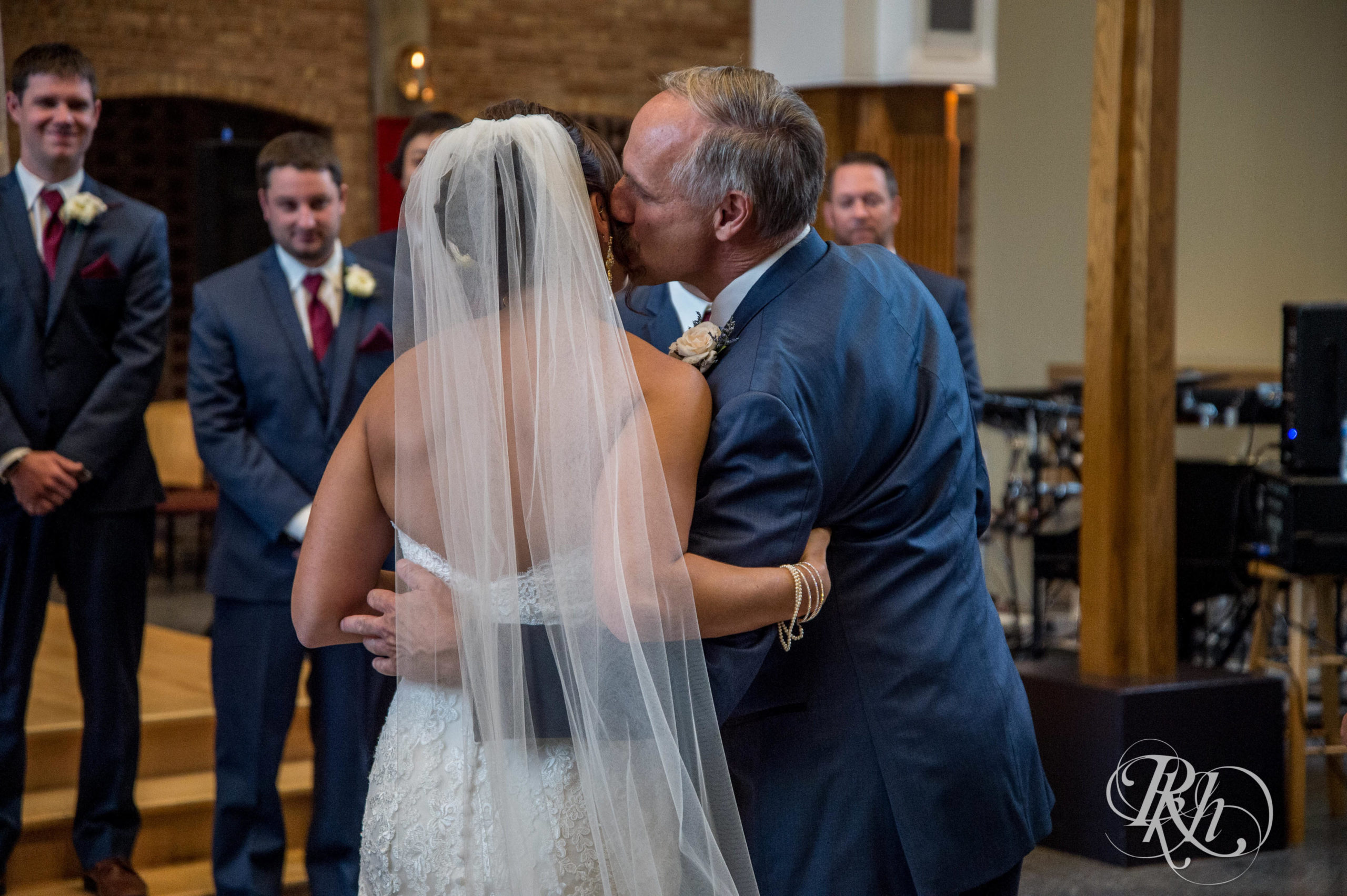Dad kisses bride on the cheek at wedding ceremony in Minneapolis, Minnesota.