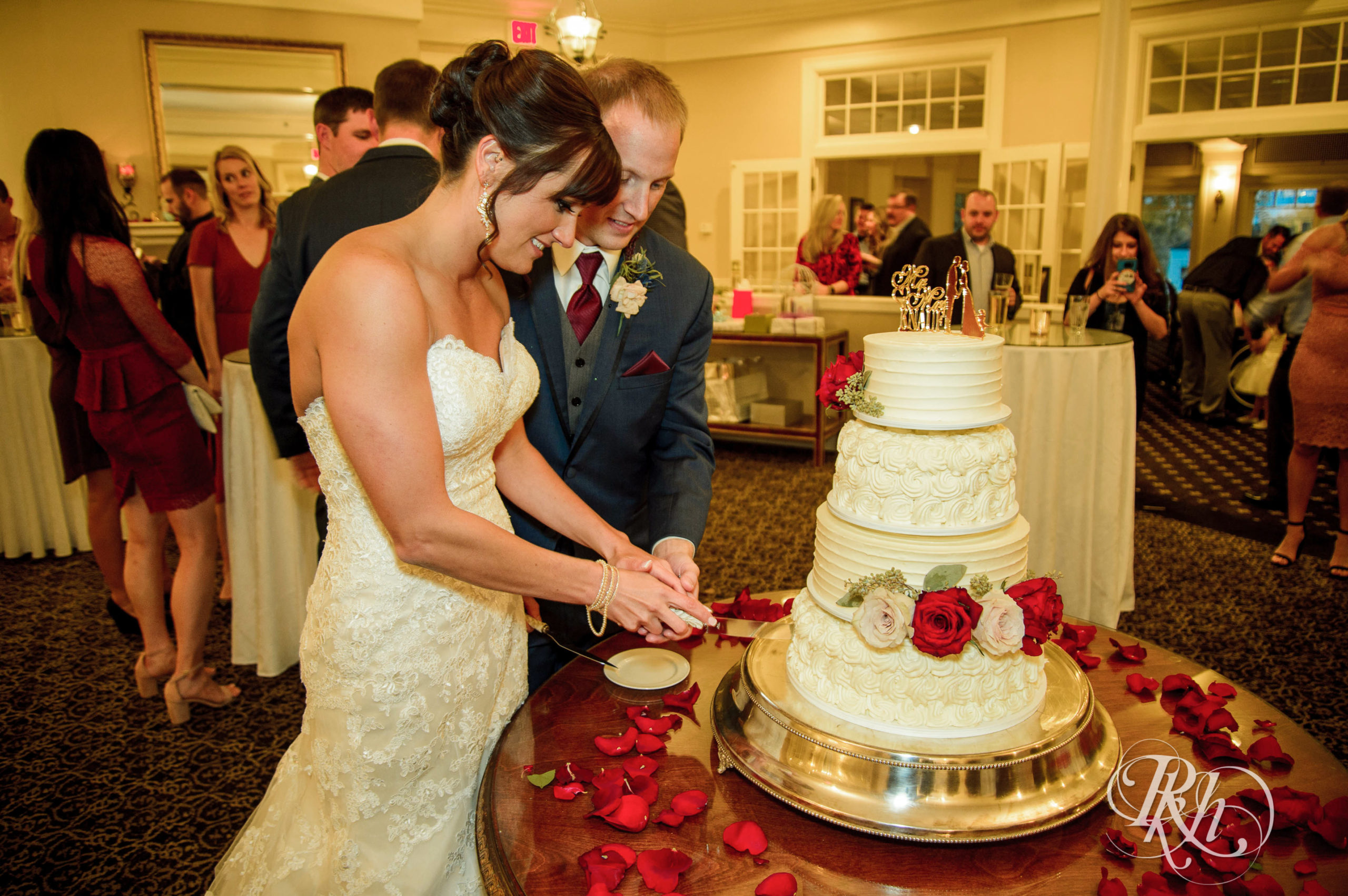 Bride and groom cut cake on fall wedding day at Minneapolis Golf Club in Minneapolis, Minnesota.