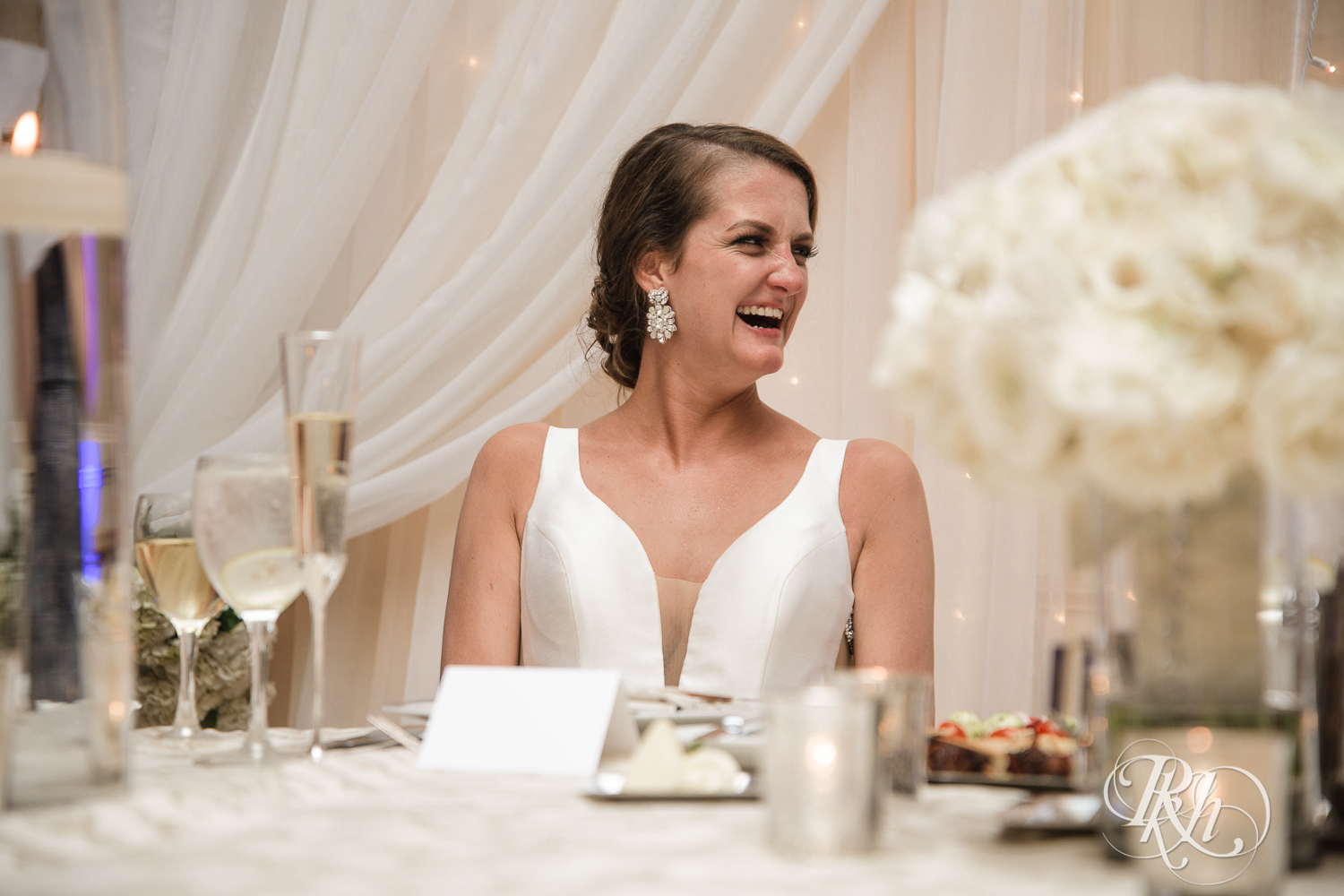 Bride and groom smile during speeches at The Saint Paul Hotel in Saint Paul, Minnesota.