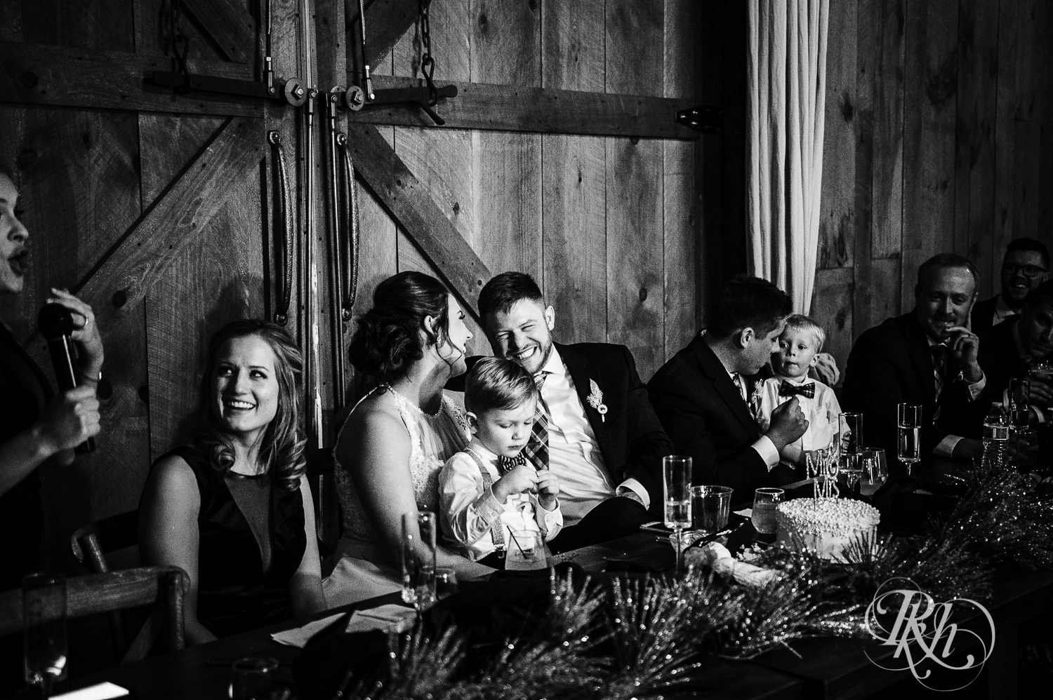 Bride and groom sit at head table during wedding reception with their sons at Creekside Farm in Rush City, Minnesota.