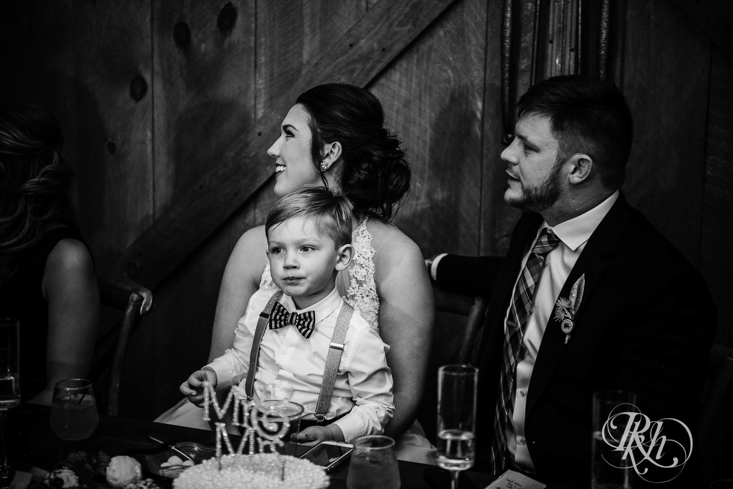 Bride and groom sit at head table during wedding reception with their sons at Creekside Farm in Rush City, Minnesota.