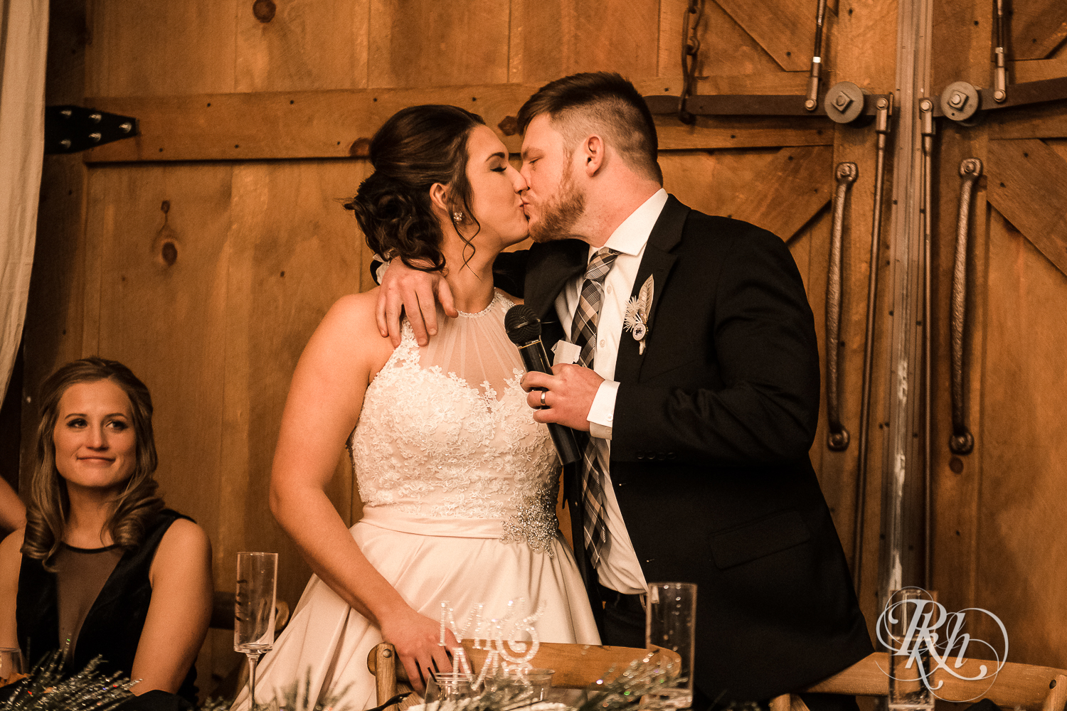 Bride and groom kiss during wedding speeches at Creekside Farm in Rush City, Minnesota.