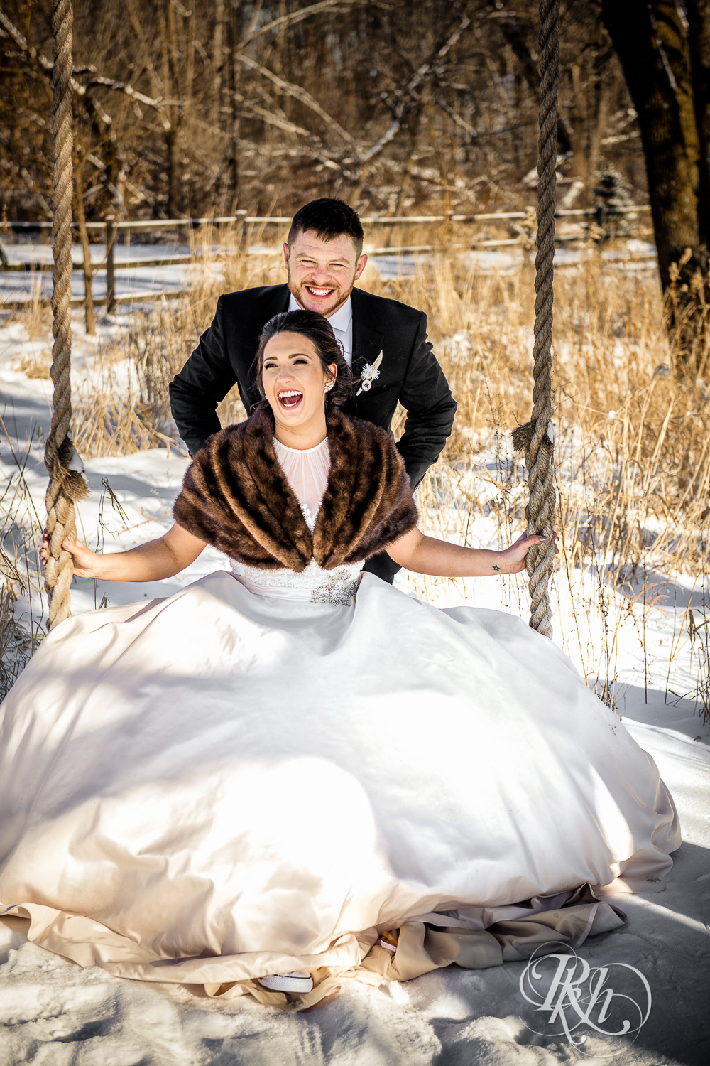 Bride and groom laugh in the snow during winter wedding at Creekside Farm in Rush City, Minnesota.