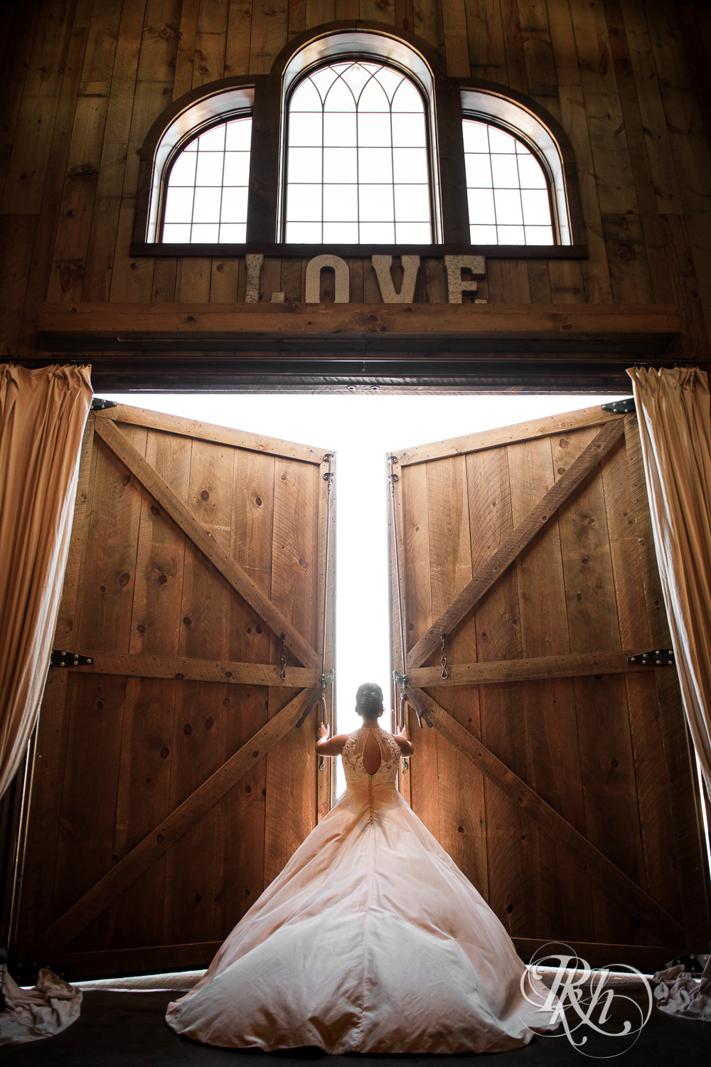 Bride opens the barn doors during winter wedding at Creekside Farm in Rush City, Minnesota.