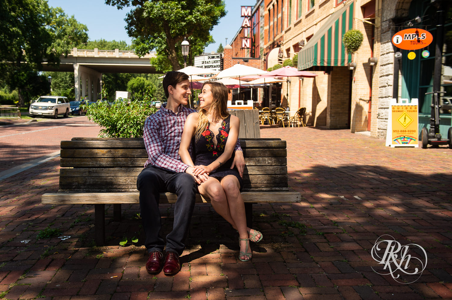 Man and woman in black lace dress sit on bench in Saint Anthony Main in Minneapolis, Minnesota.