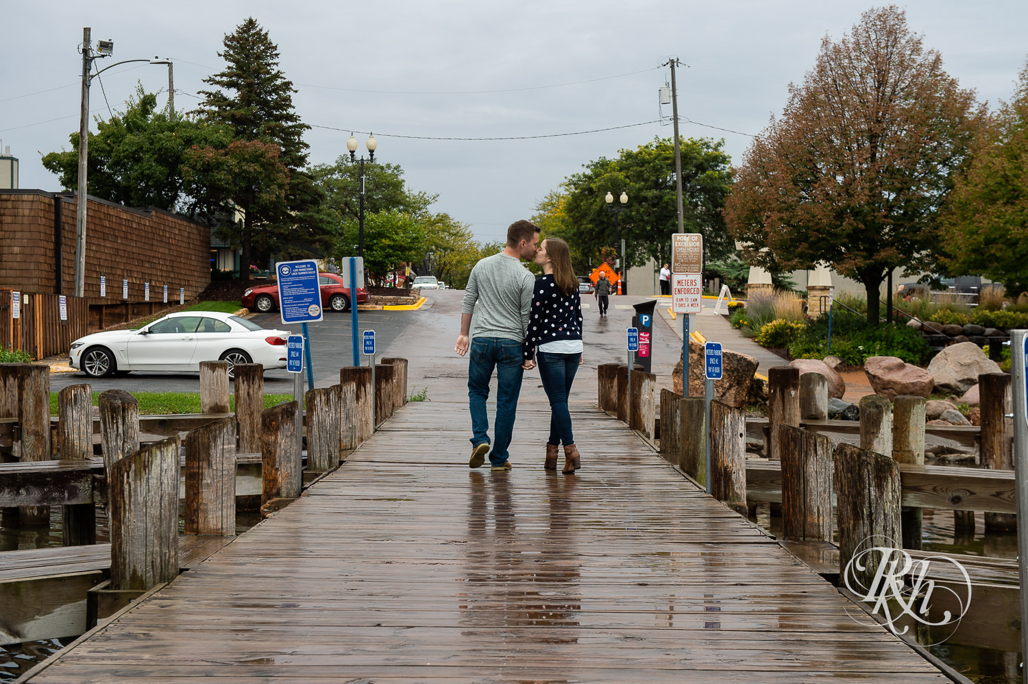 Man and woman kiss walking on dock during rain in Excelsior, Minnesota.