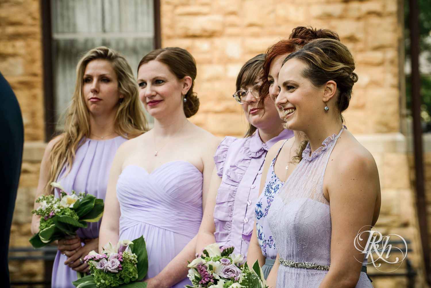 Bridesmaids smile during wedding ceremony at Summit Manor Reception House in Saint Paul, Minnesota.