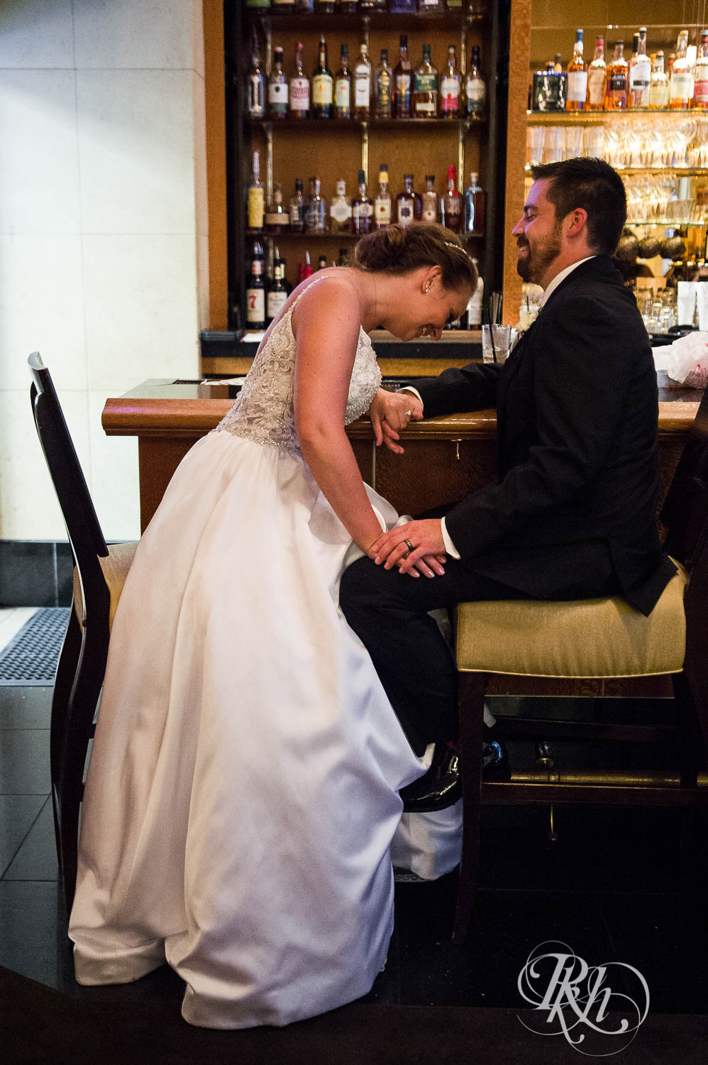 Bride and groom laugh at bar at Crowne Plaza Minneapolis Northstar Downtown in Minneapolis, Minnesota.