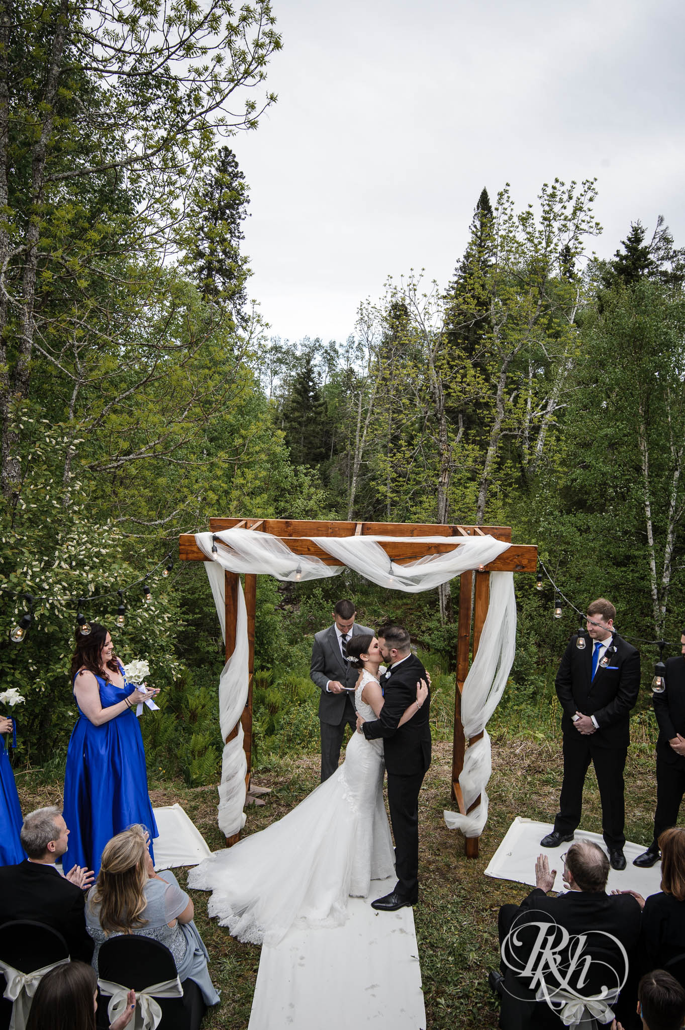 Bride and groom kiss during backyard wedding ceremony in North Shore in Minnesota.