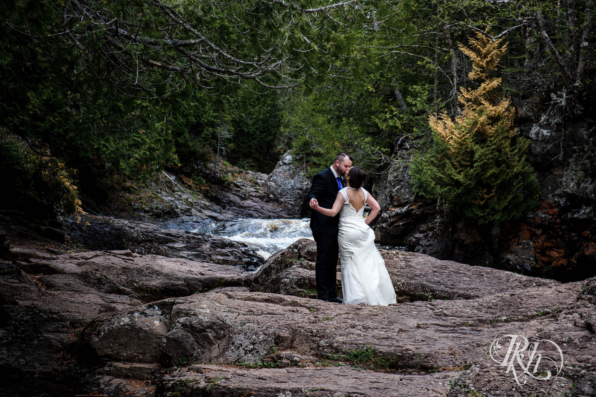Bride and groom kissing at the bottom of a waterfall.