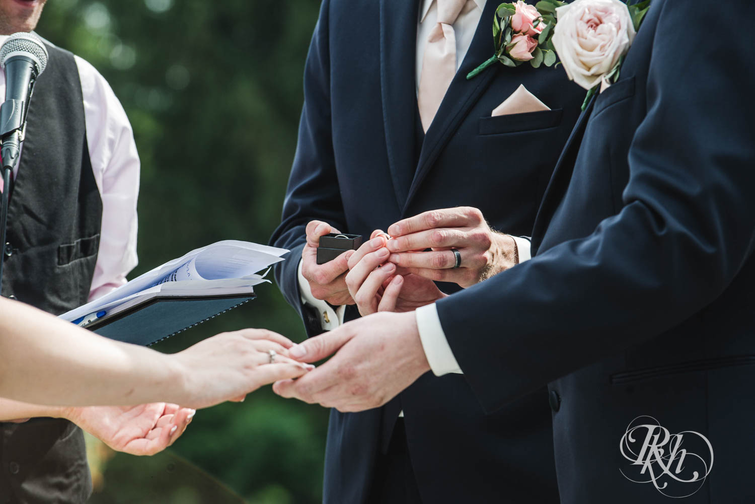 Bride and groom exchange rings during outdoor wedding ceremony at Earle Brown Heritage Center in Brooklyn Center, Minnesota.