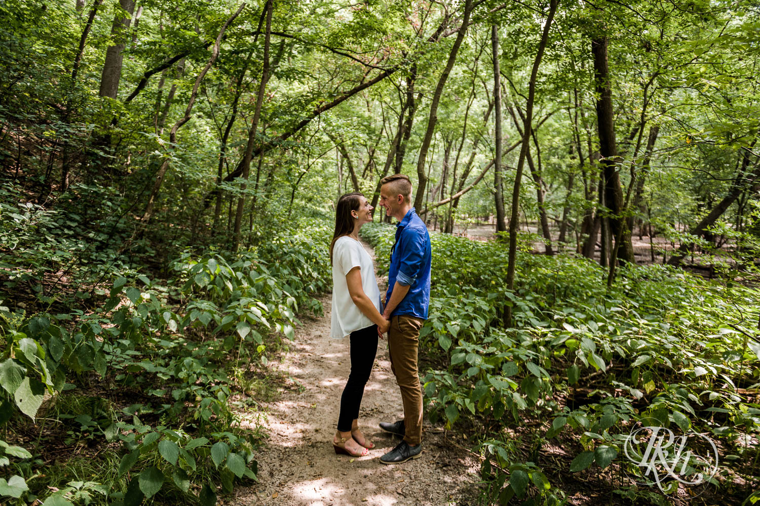 Man and woman smile during engagement photos at Hidden Falls Regional Park in Saint Paul, Minnesota.