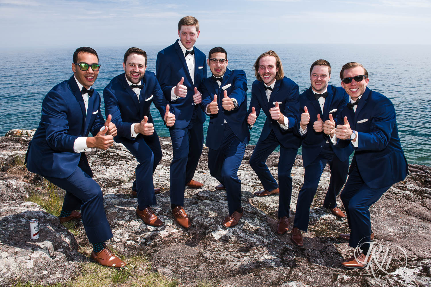 Groomsmen smile on cliff in front of Lake Superior in Bluefin Bay wedding in Tofte, Minnesota.