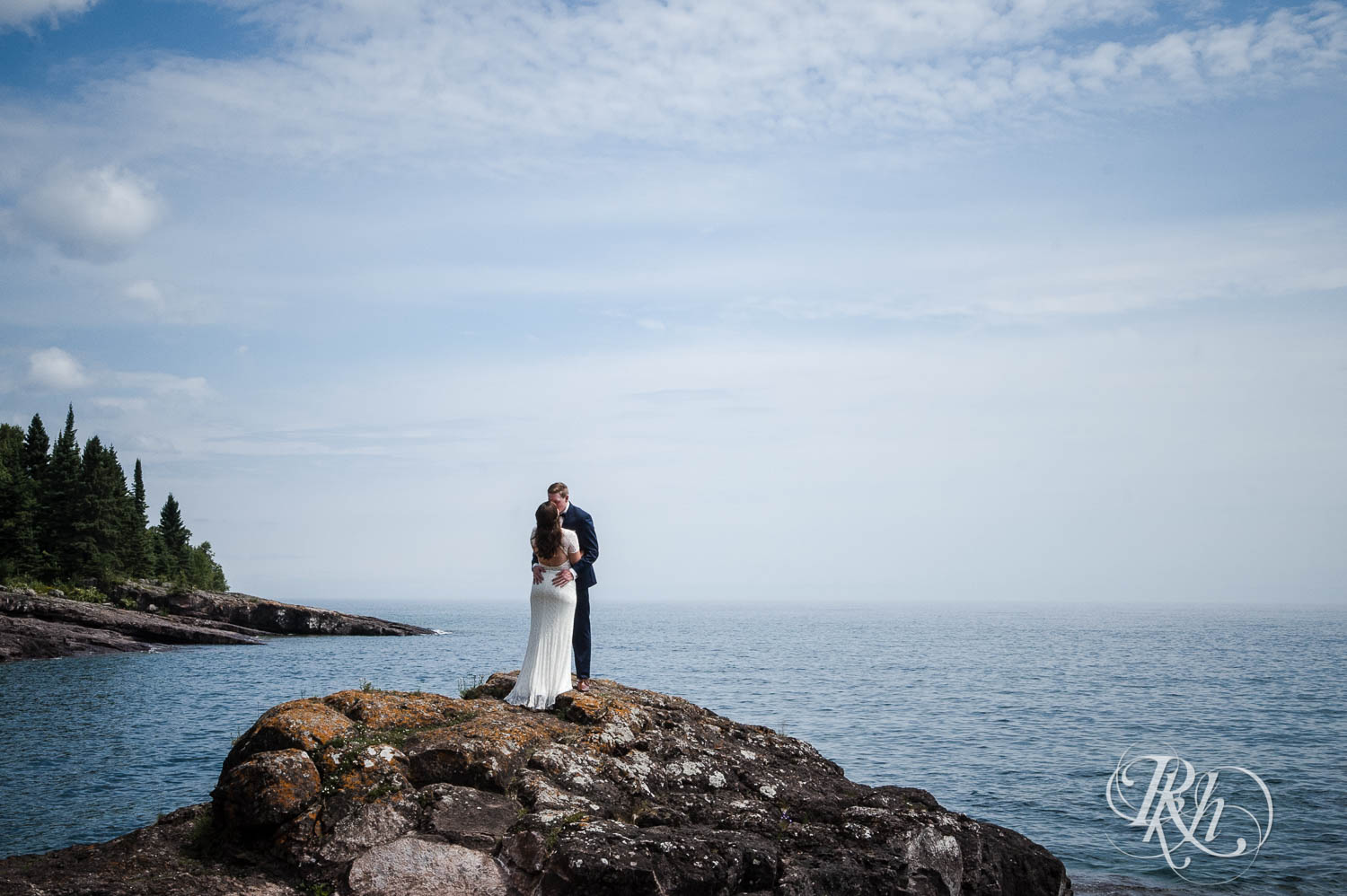 Bride and groom kiss on cliff in Bluefin Bay in Tofte, Minnesota.