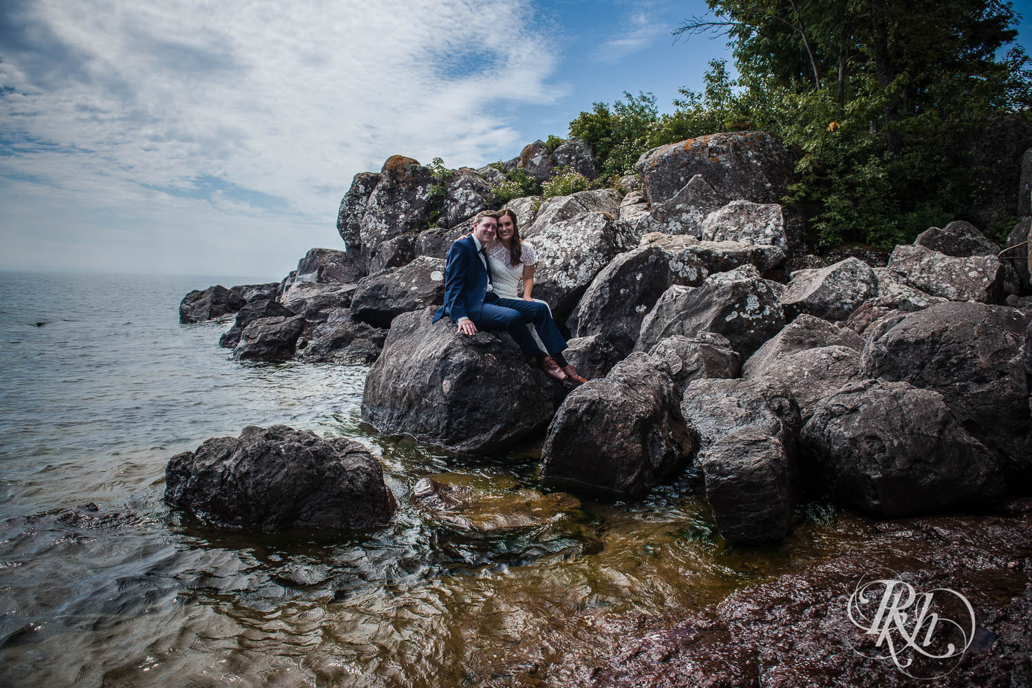 Bride and groom smile on rocks in Bluefin Bay in Tofte, Minnesota.