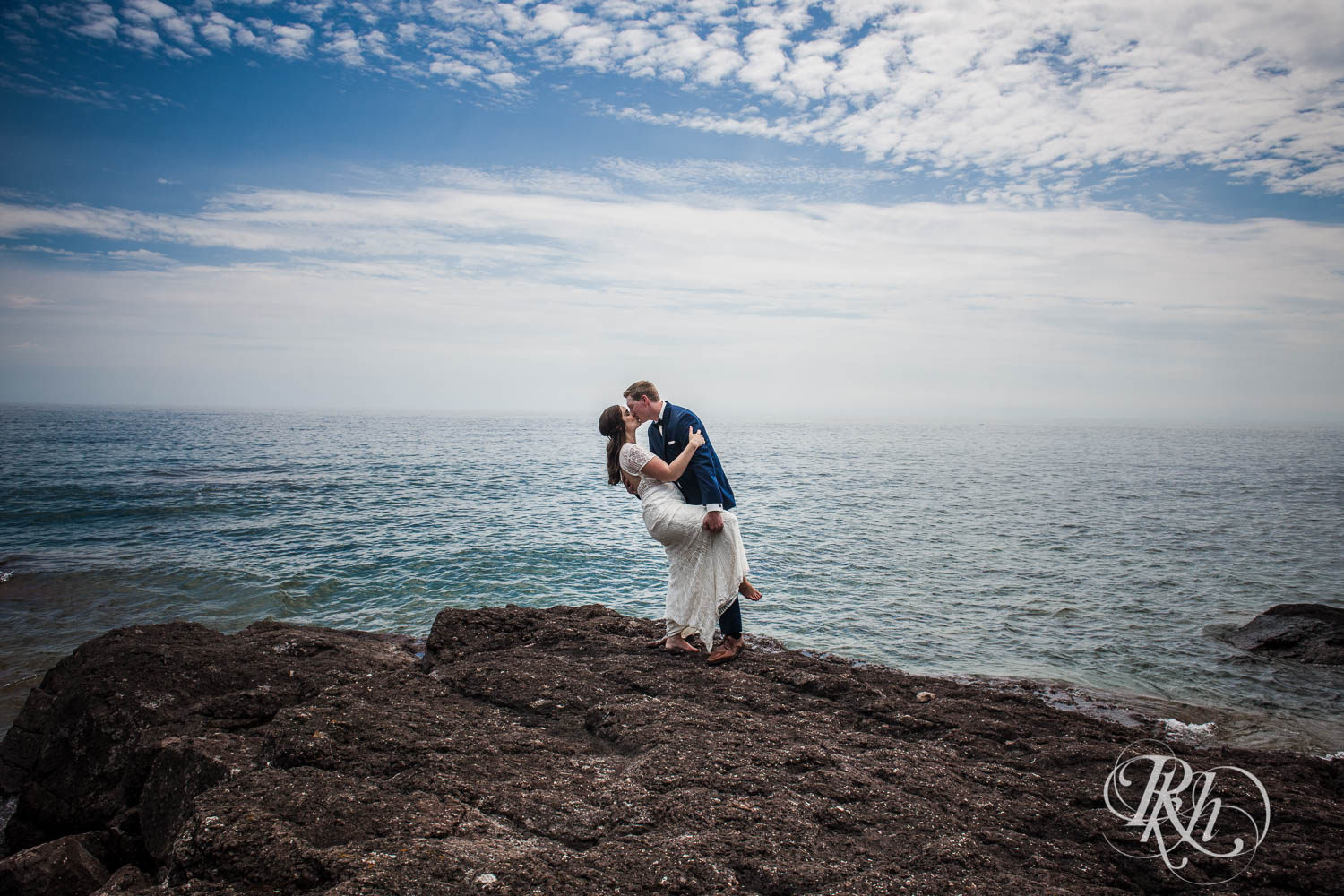 Bride and groom dip and kiss on Lake Superior