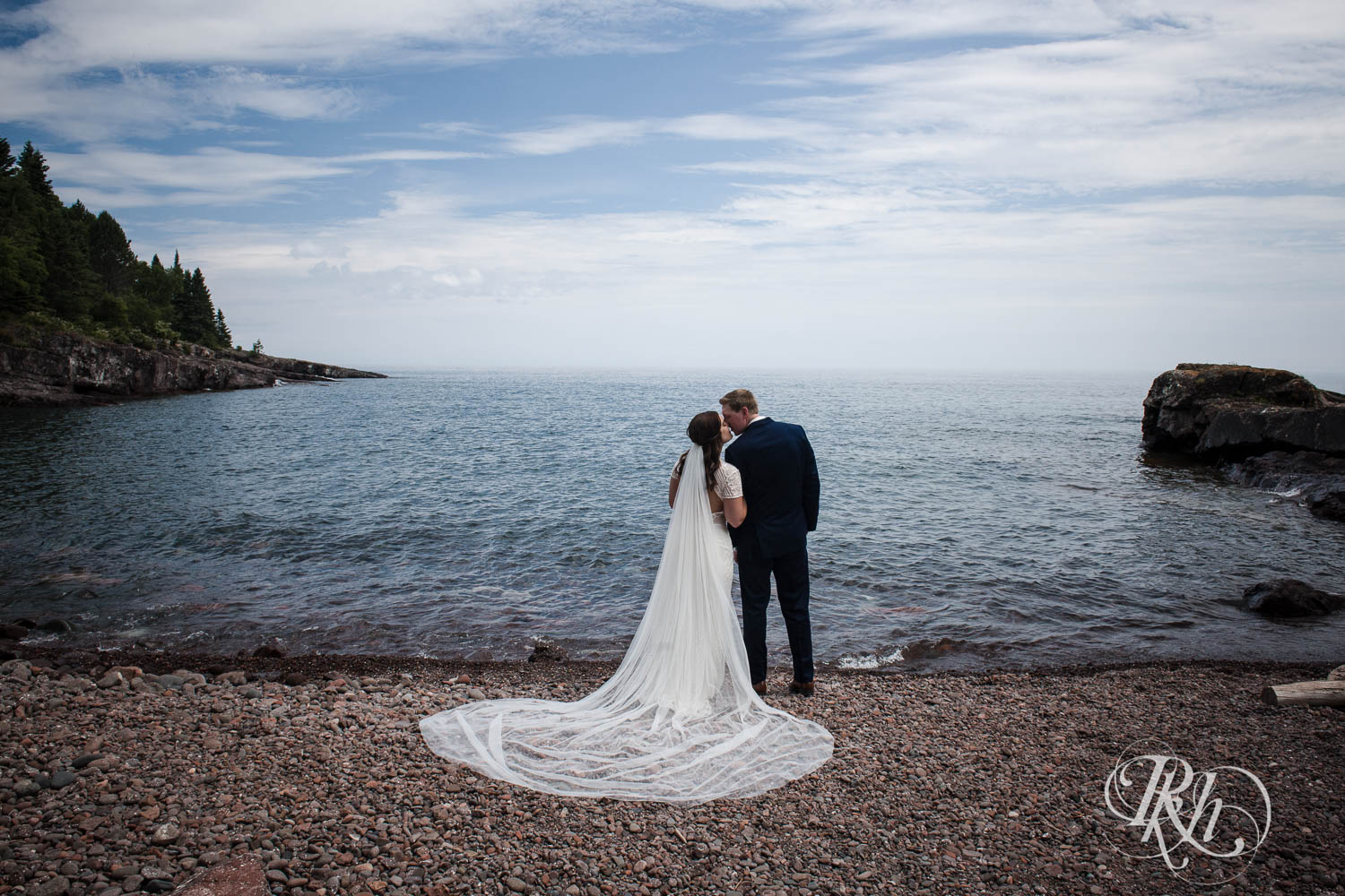 Bride and groom kiss on beach in Bluefin Bay in Tofte, Minnesota.