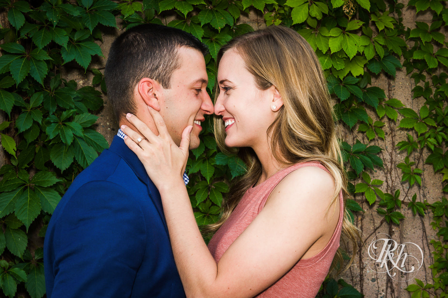 Man in blue suit and woman in pink dress smile during Centennial Lakes Park engagement photography in Edina, Minnesota.