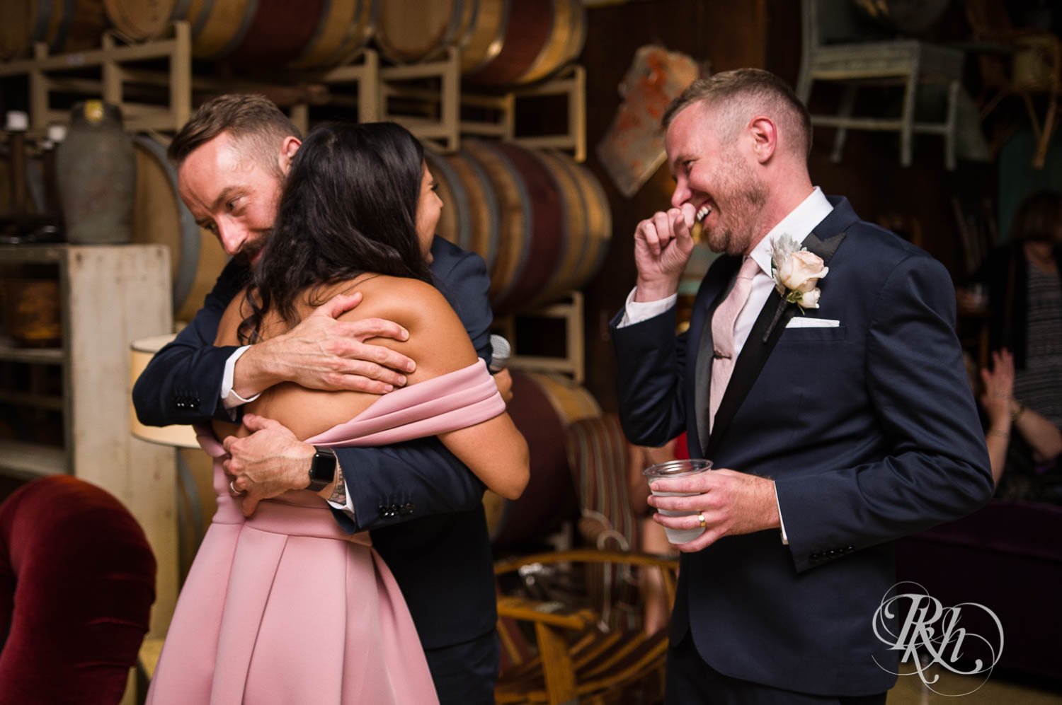 Grooms laugh during wedding reception speeches at Warehouse Winery wedding in Saint Louis Park, Minnesota.
