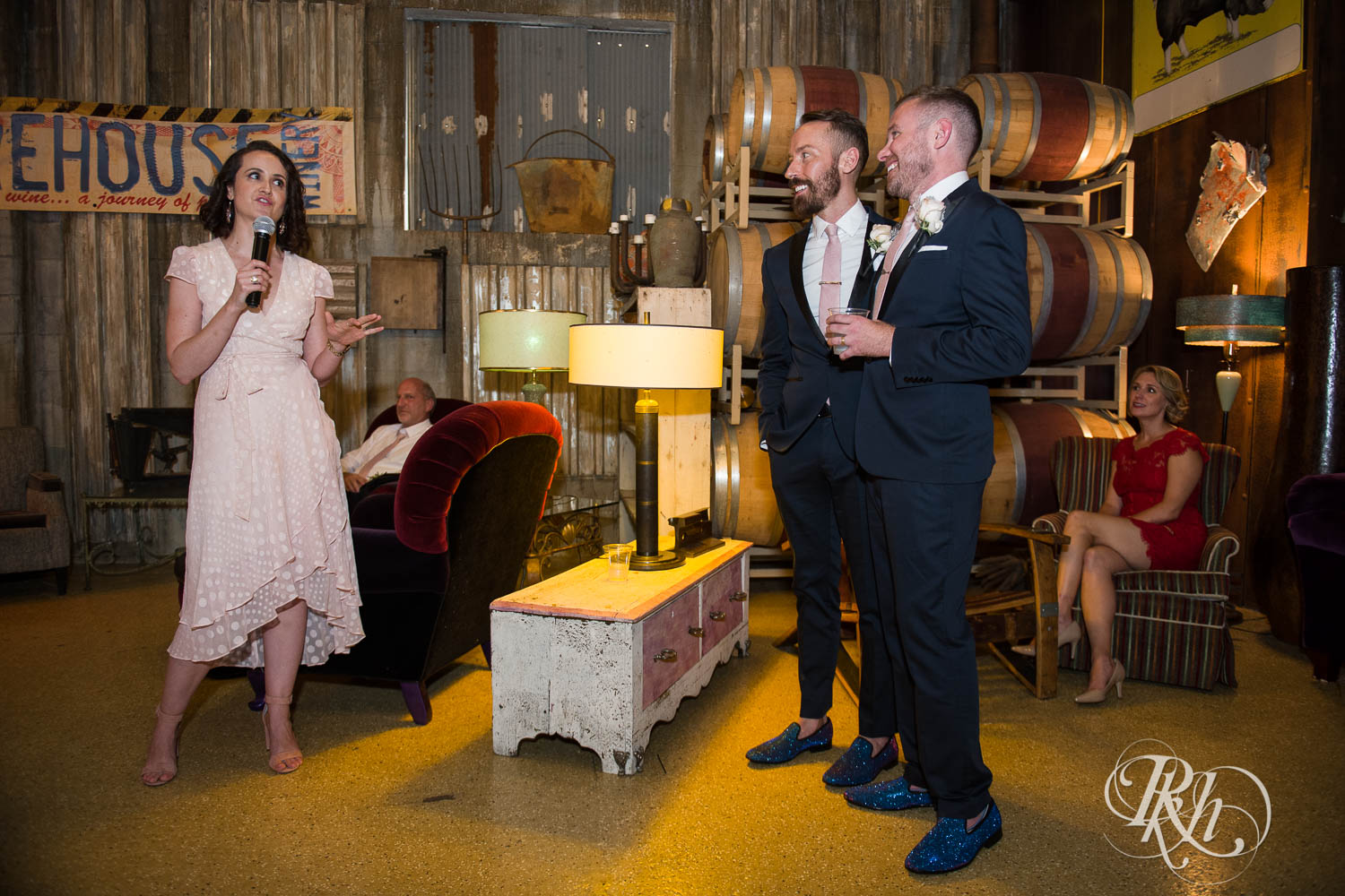 Grooms laugh during wedding reception speeches at Warehouse Winery wedding in Saint Louis Park, Minnesota.