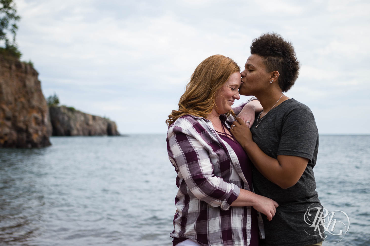 Two women kiss during lesbian black beach engagement photography