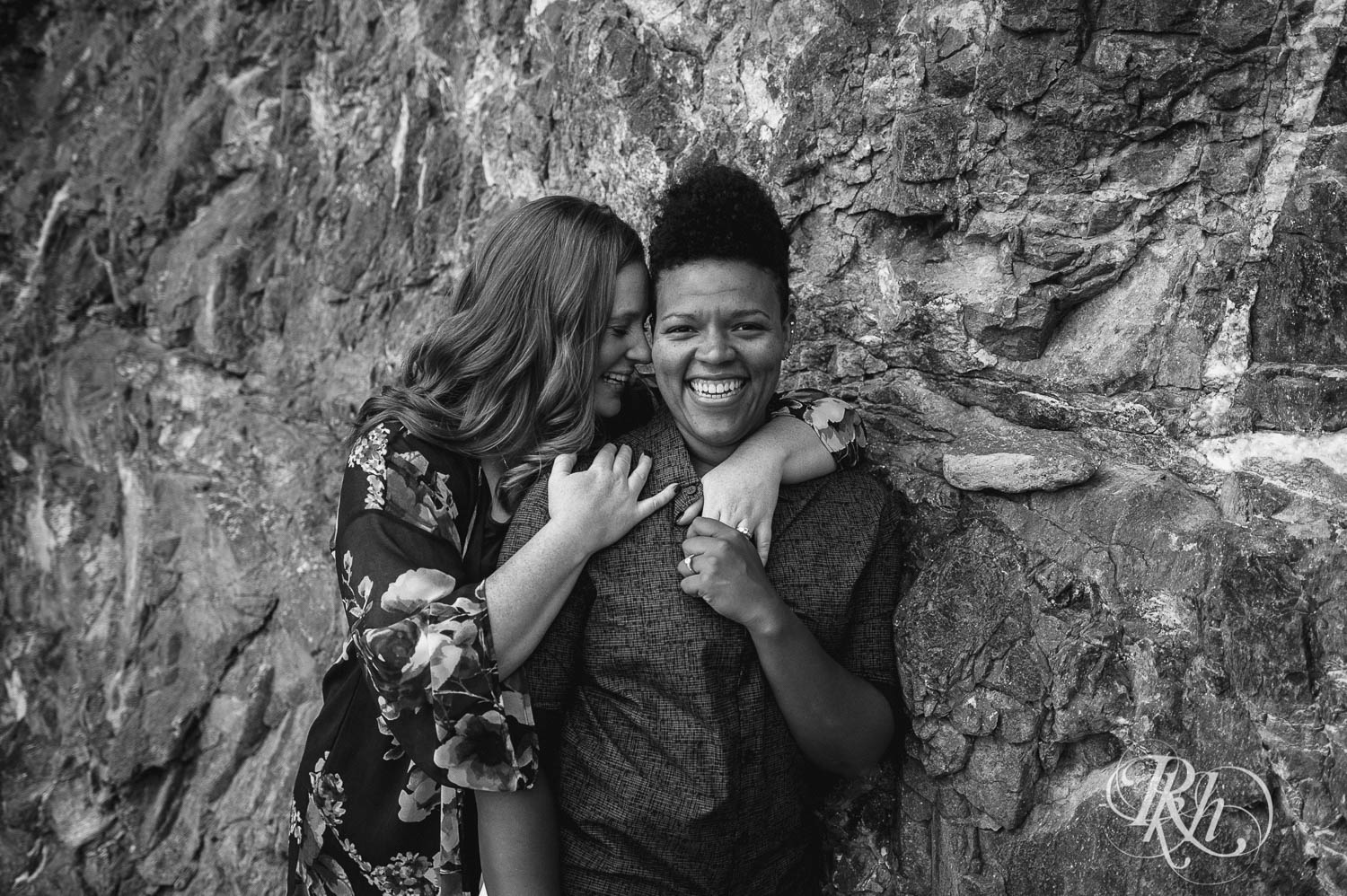 Two women smile during lesbian black beach engagement photography