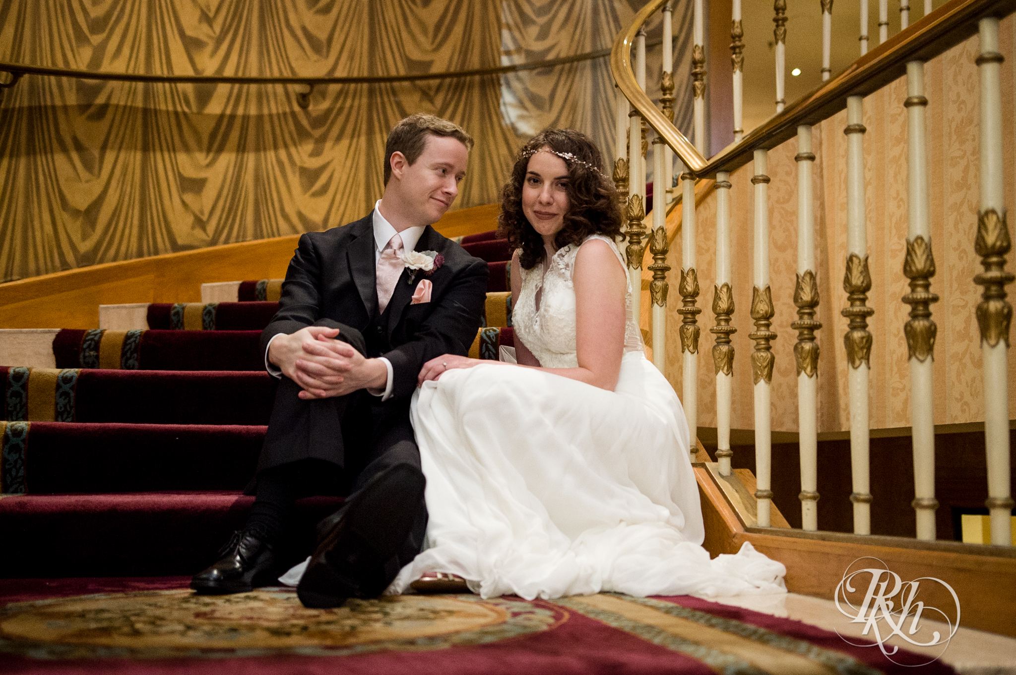 Bride and groom smile on stairs at the Saint Paul Hotel in Saint Paul, Minnesota.