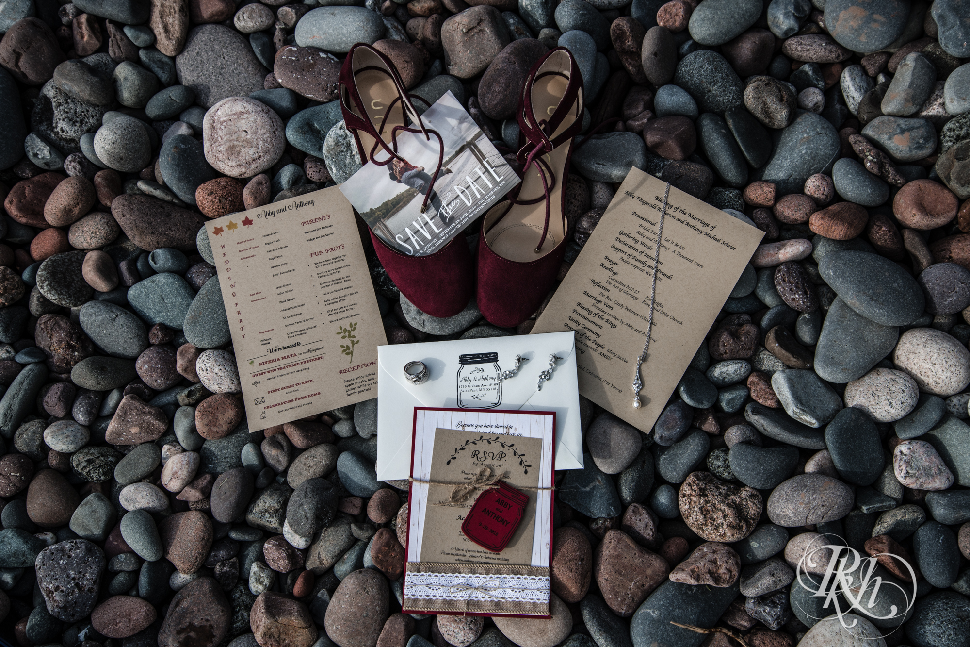Wedding invites, save the dates, red shoes, and jewelry on rocky beach in the North Shore, Minnesota.