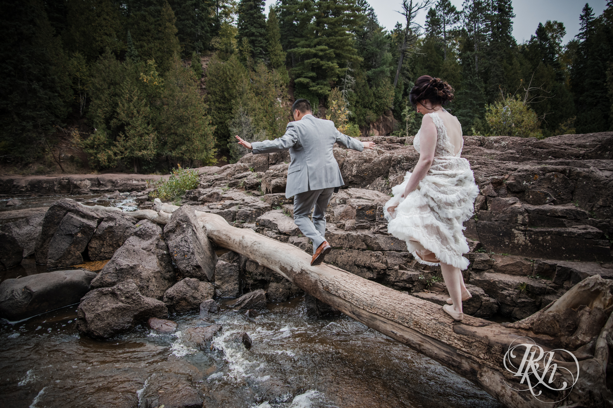 bride and groom walking across log
