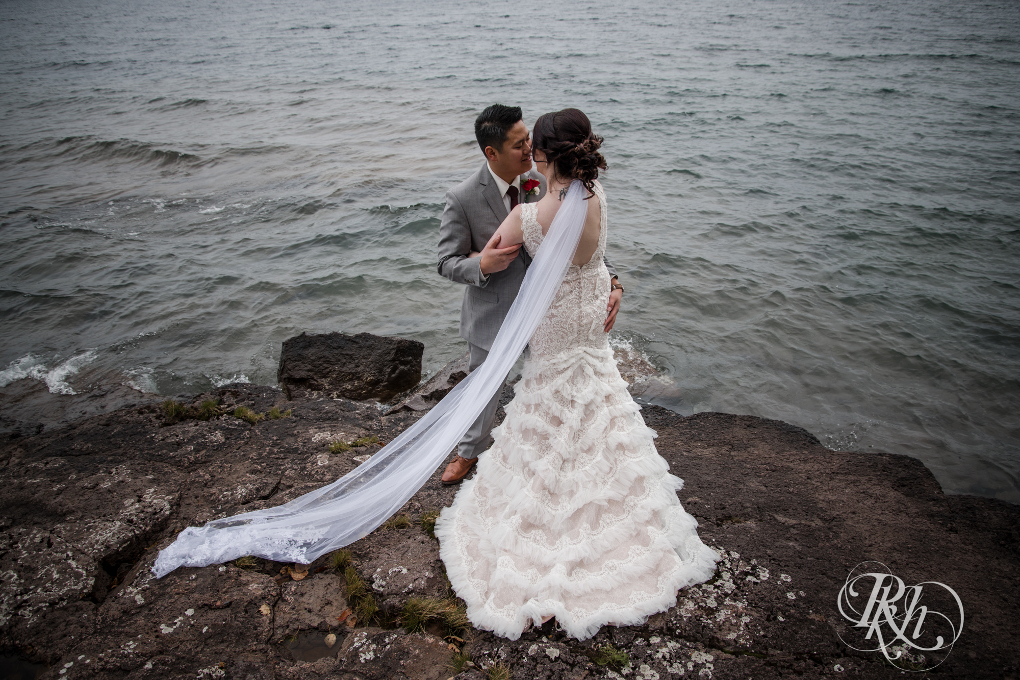 Bride and groom kiss in front of Lake Superior at Grand Superior Lodge in Two Harbors, Minnesota.