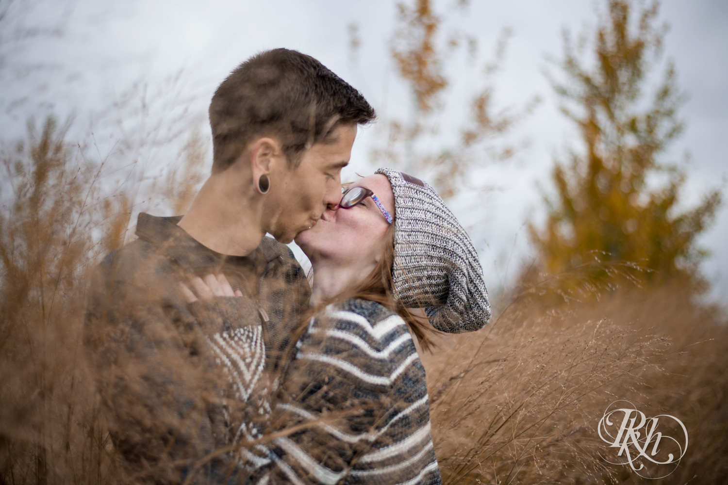 Man kisses woman in glasses and hat at Whitetail Woods in Farmington, Minnesota. 