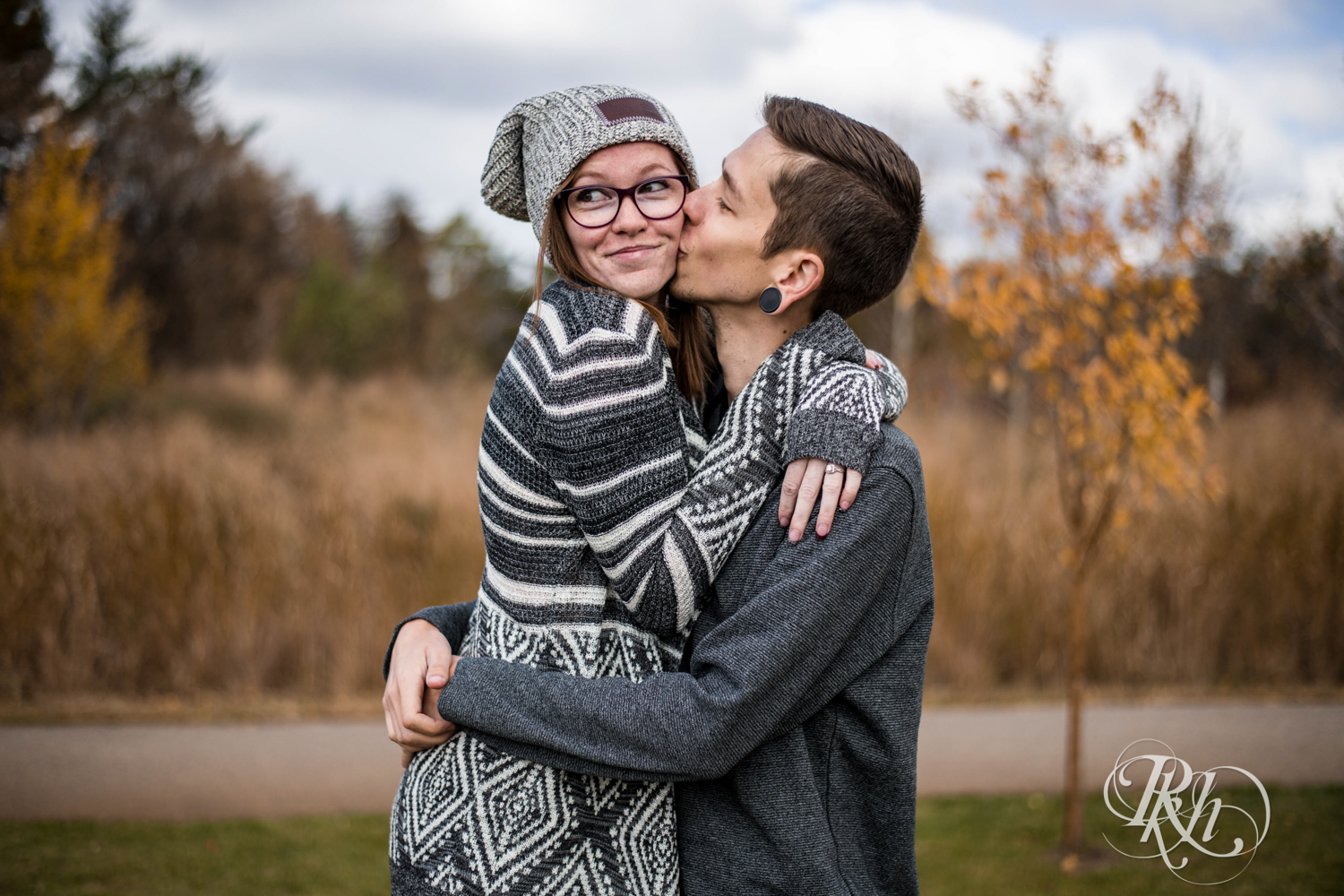 Man kisses woman in glasses and hat at Whitetail Woods in Farmington, Minnesota. 