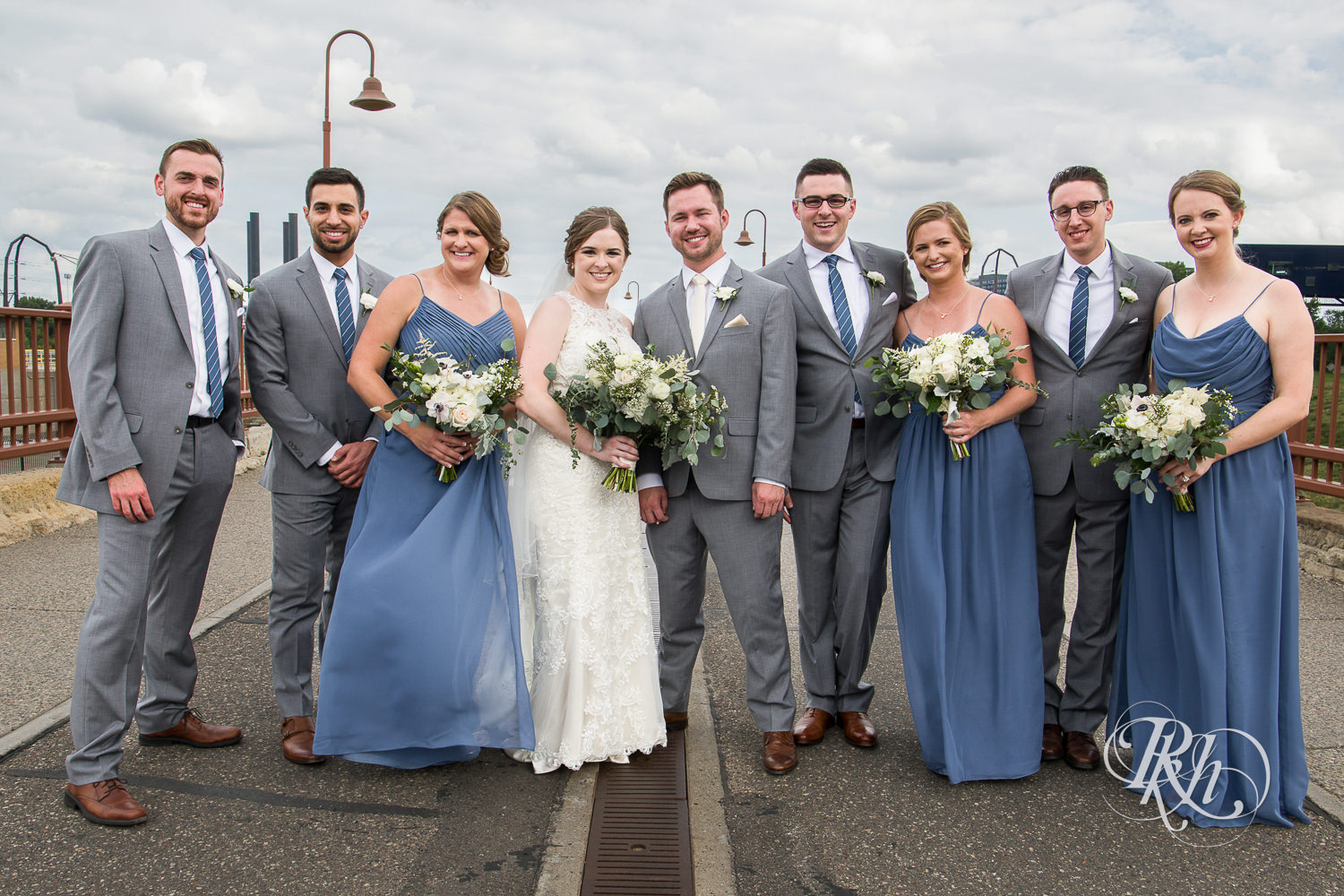 Wedding party smiles on the Stone Arch Bridge in Minneapolis, Minnesota.