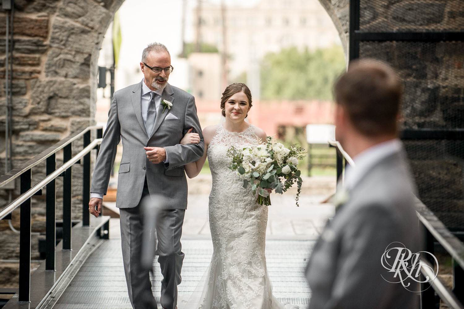 Bride walks down the aisle during outdoor wedding ceremony in Mill City Museum in Minneapolis, Minnesota.