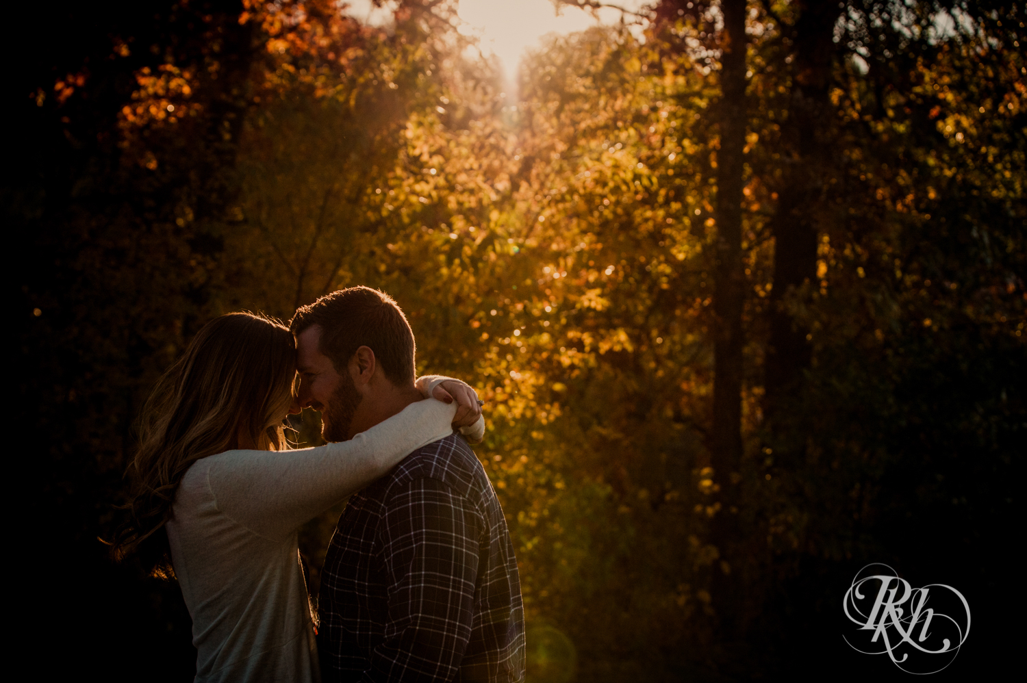 Man and woman smile during golden hour engagement photos at Lebanon Hills in Eagan, Minnesota.
