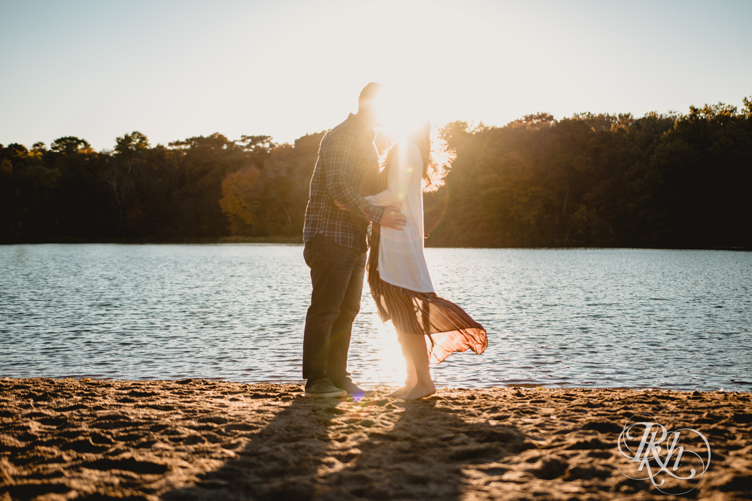 Man and woman kiss on beach during golden hour engagement photos at Lebanon Hills in Eagan, Minnesota.