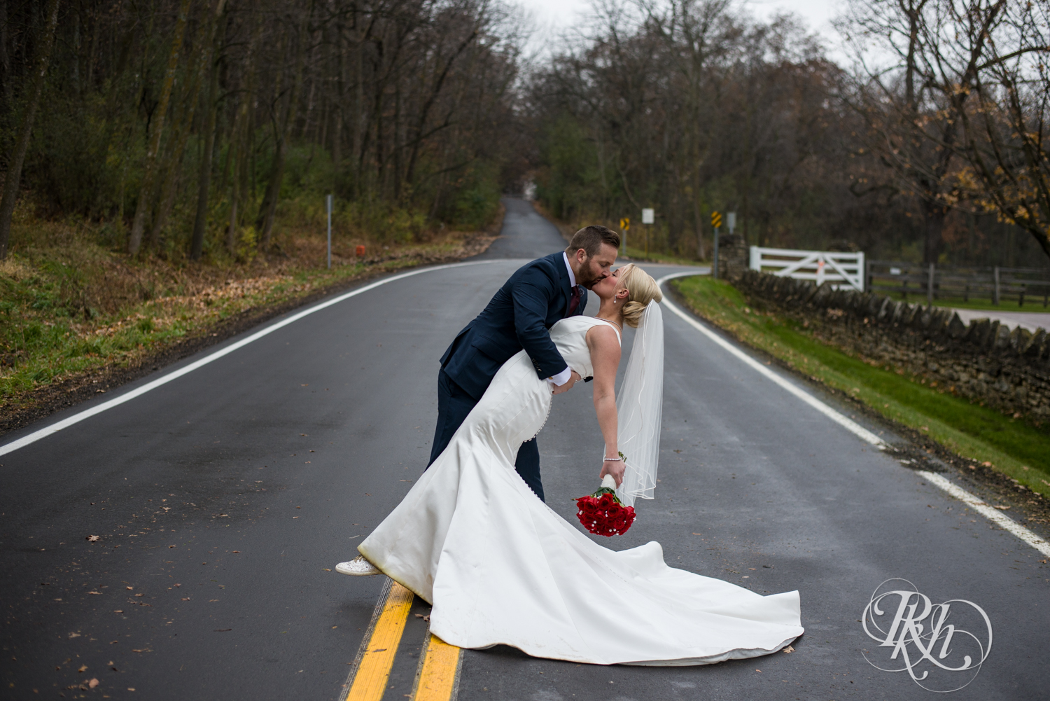 Bride and groom kiss in the middle of the road at Mayowood Stone Barn in Rochester, Minnesota.