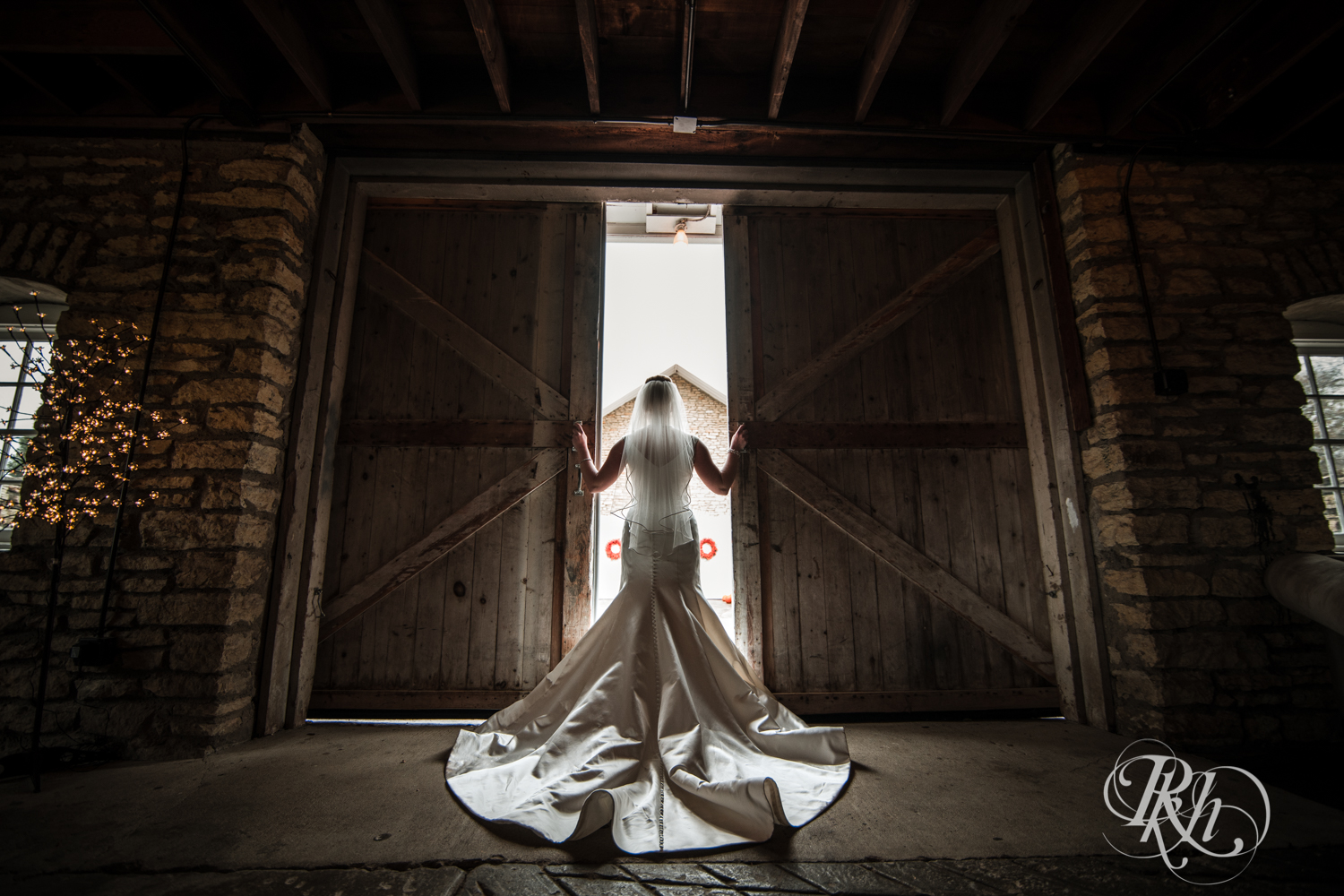 Bride opens barn doors at Mayowood Stone Barn in Rochester, Minnesota.