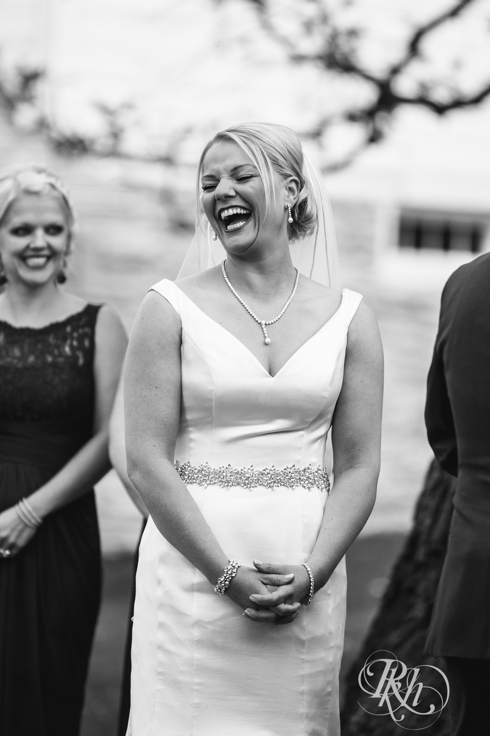 Bride and groom laugh during outdoor wedding ceremony at Mayowood Stone Barn in Rochester, Minnesota.