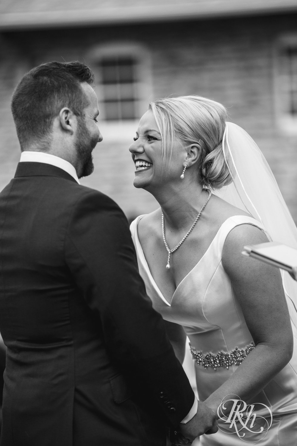 Bride and groom smile during outdoor wedding ceremony at Mayowood Stone Barn in Rochester, Minnesota.