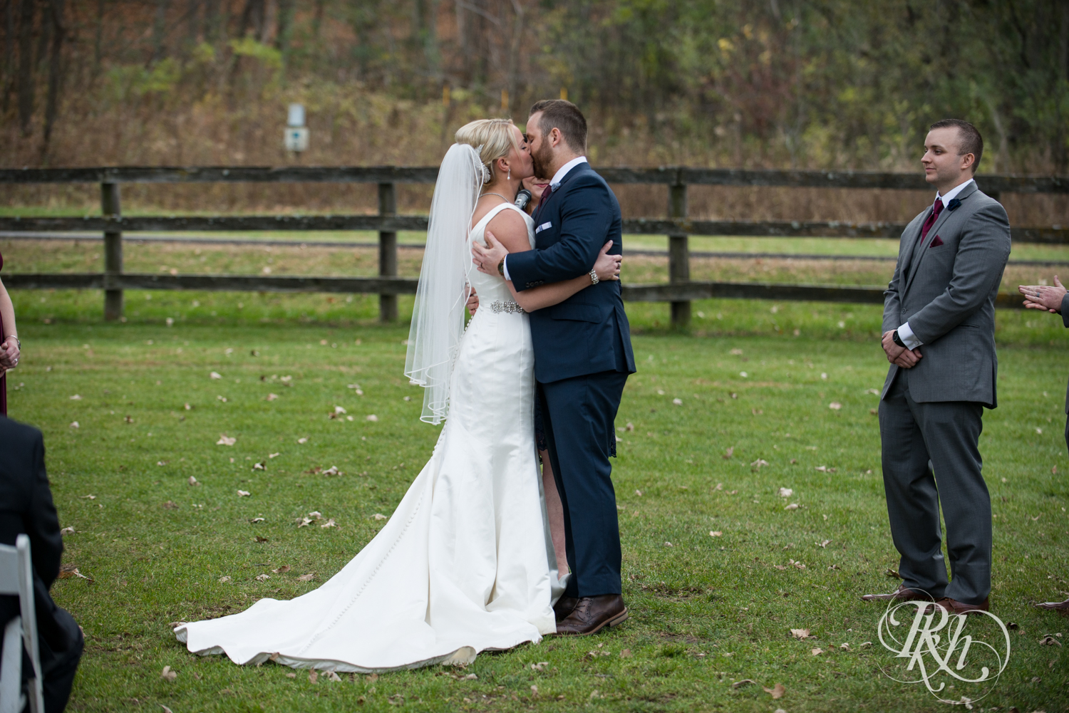 Bride and groom kiss during outdoor wedding ceremony at Mayowood Stone Barn in Rochester, Minnesota.