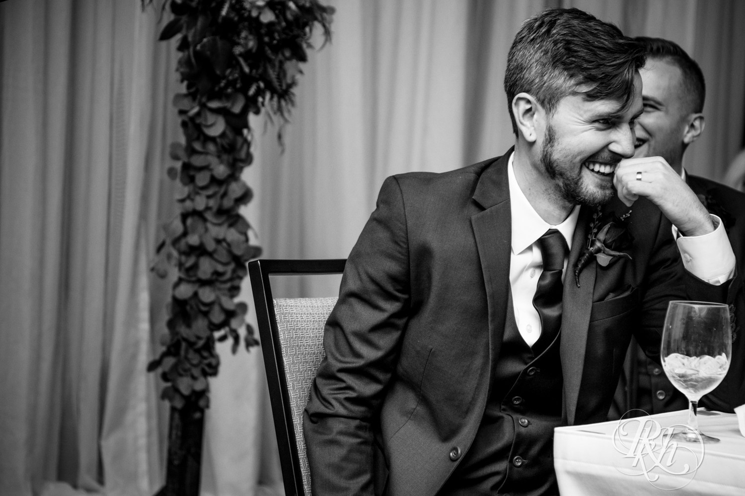 Groom laughs during speeches at wedding reception at at Courtyard by Marriott Minneapolis.
