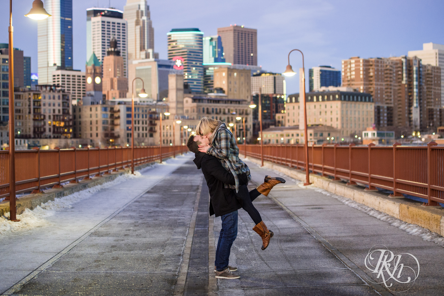 Man and woman kiss during sunrise engagement photography on Stone Arch Bridge in Minneapolis, Minnesota.