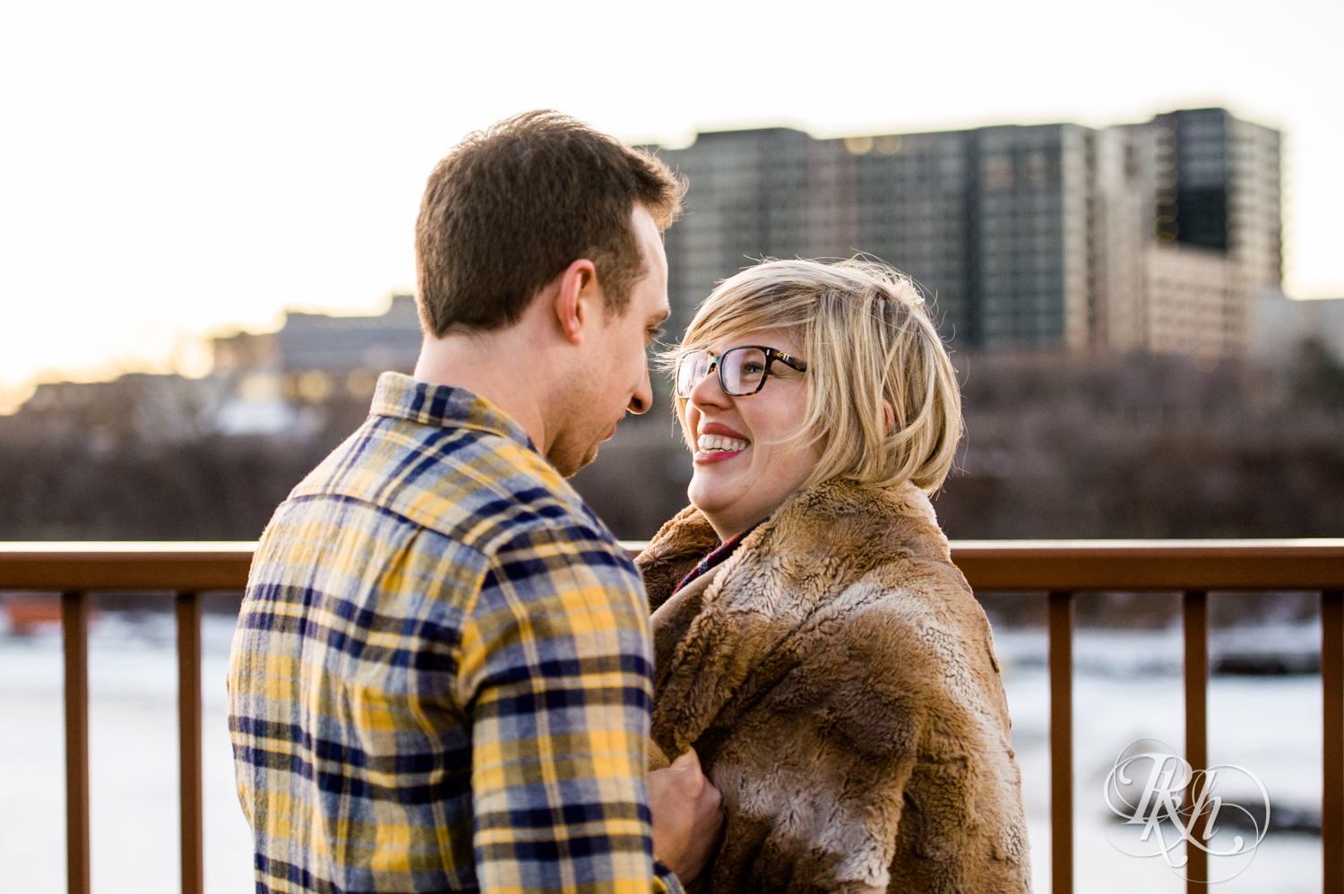 Man and woman smile during sunrise engagement photography on Stone Arch Bridge in Minneapolis, Minnesota.