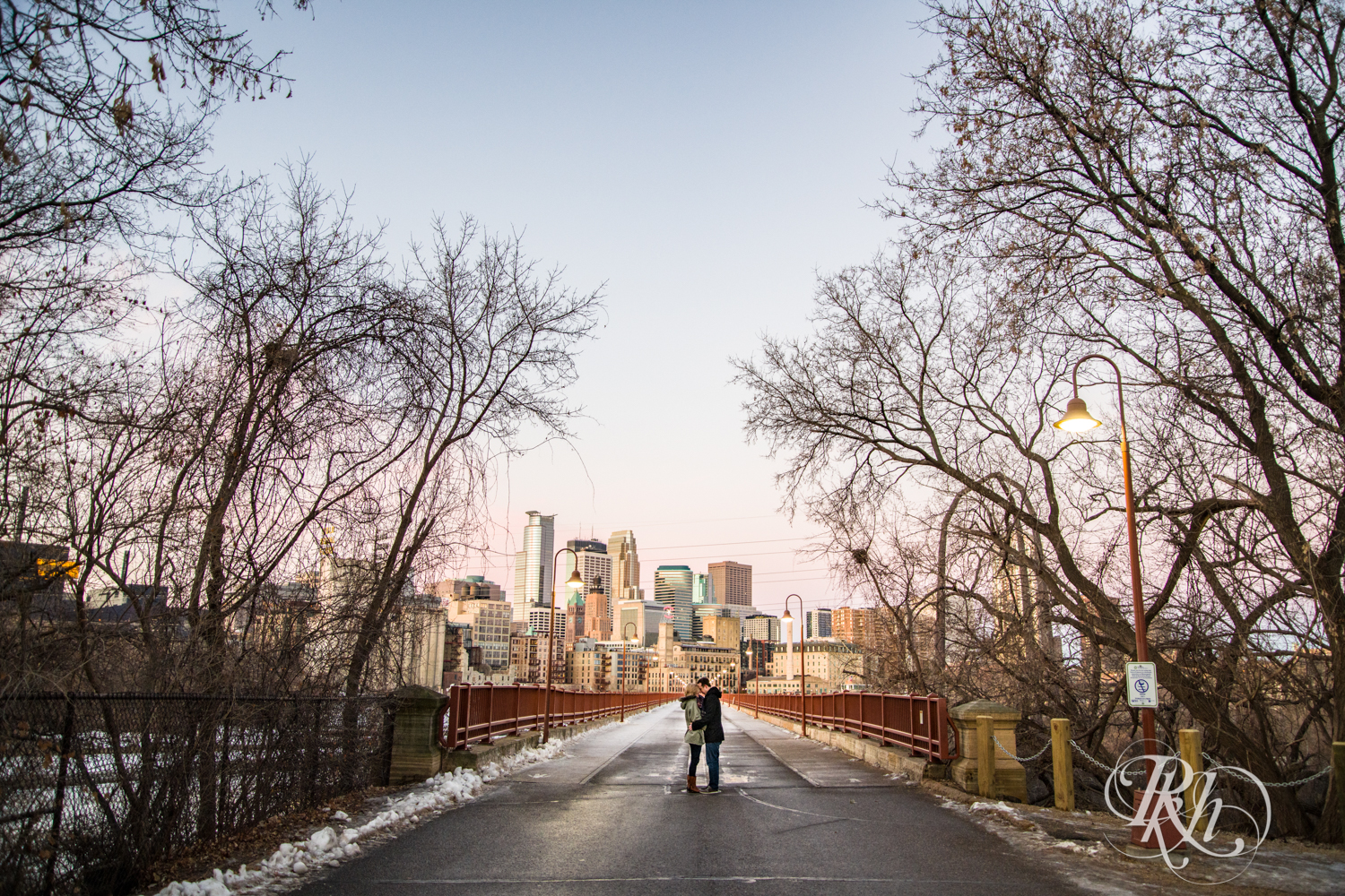 Man and woman kiss during sunrise engagement photography on Stone Arch Bridge in Minneapolis, Minnesota.